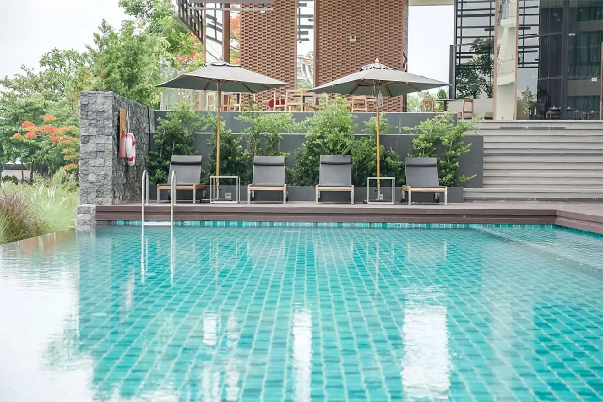 Tiled outdoor pool by day, with sun loungers and parasols on the terrace above