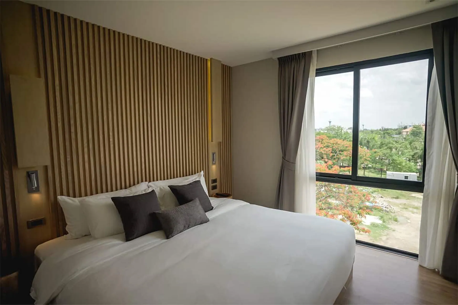 Bedroom with a double bed, a slatted timber headboard and a large window onto greenery