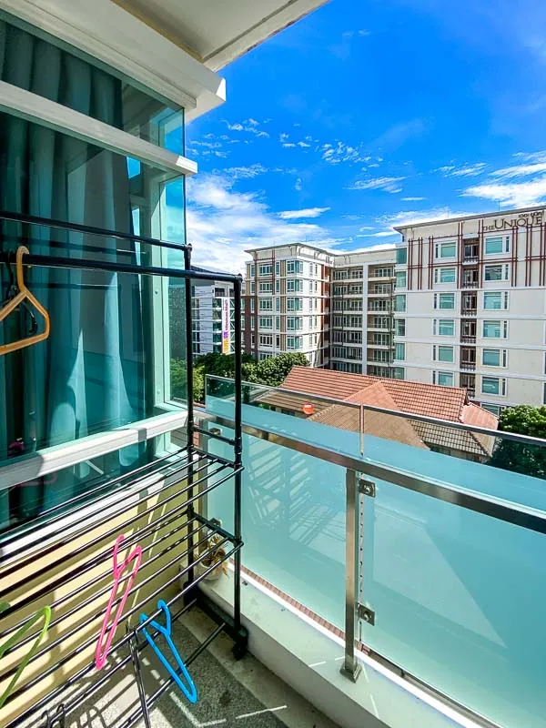 Balcony with a glass balustrade and a drying rack, looking out to the neighbouring buildings
