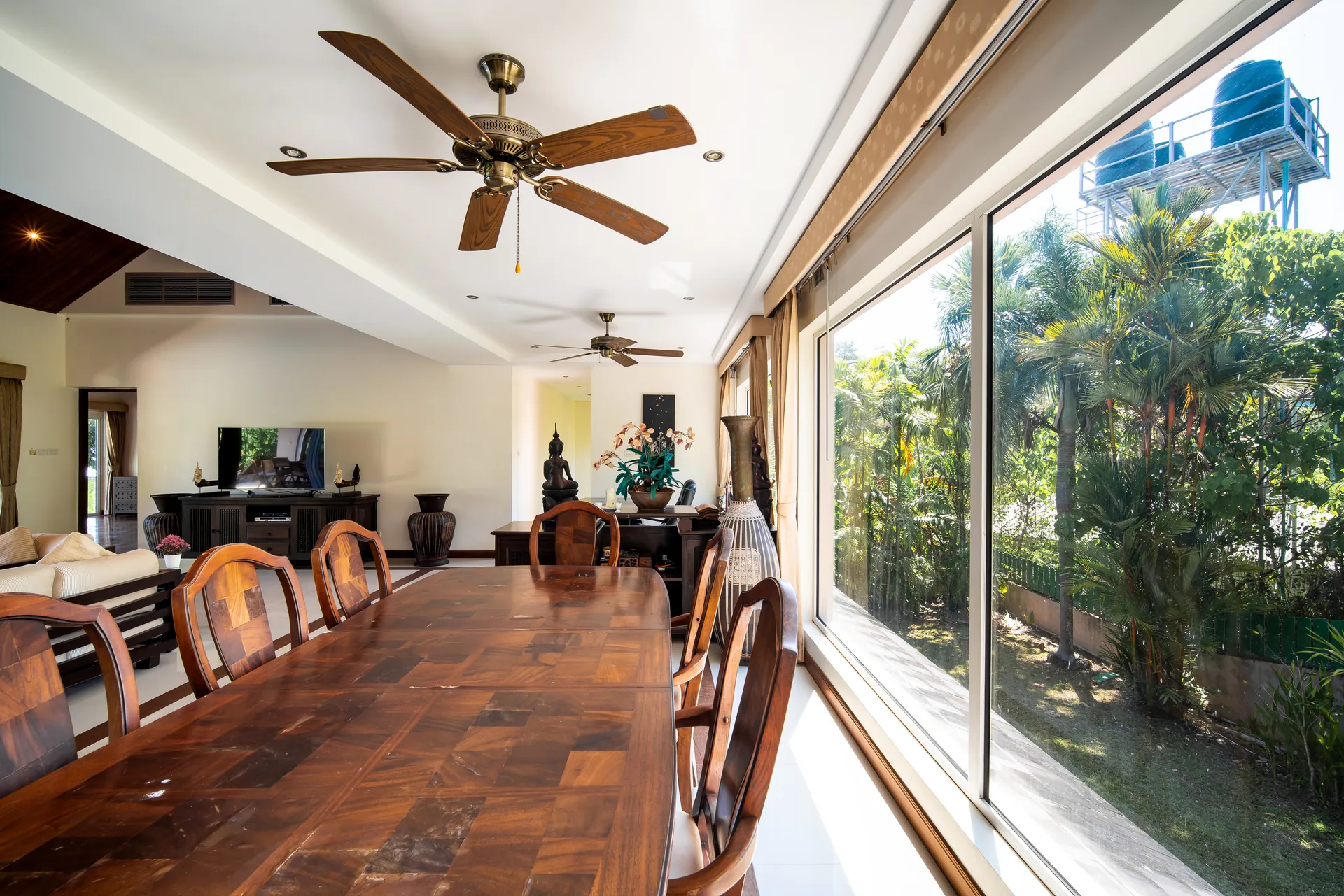 Long timber dining table beside floor-to-ceiling windows onto the garden