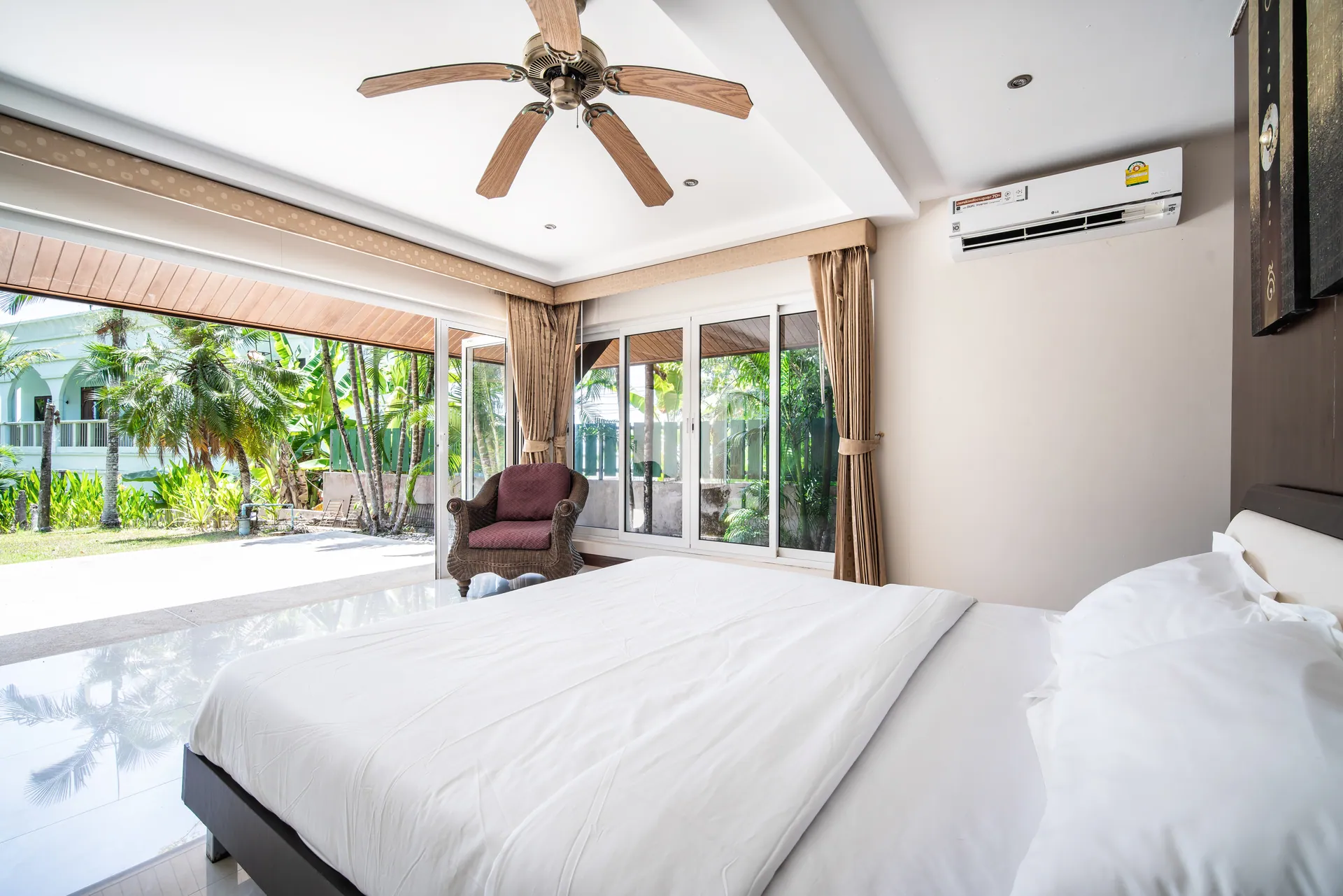 Bedroom 4 with folding glass doors to the garden, an armchair and a ceiling fan