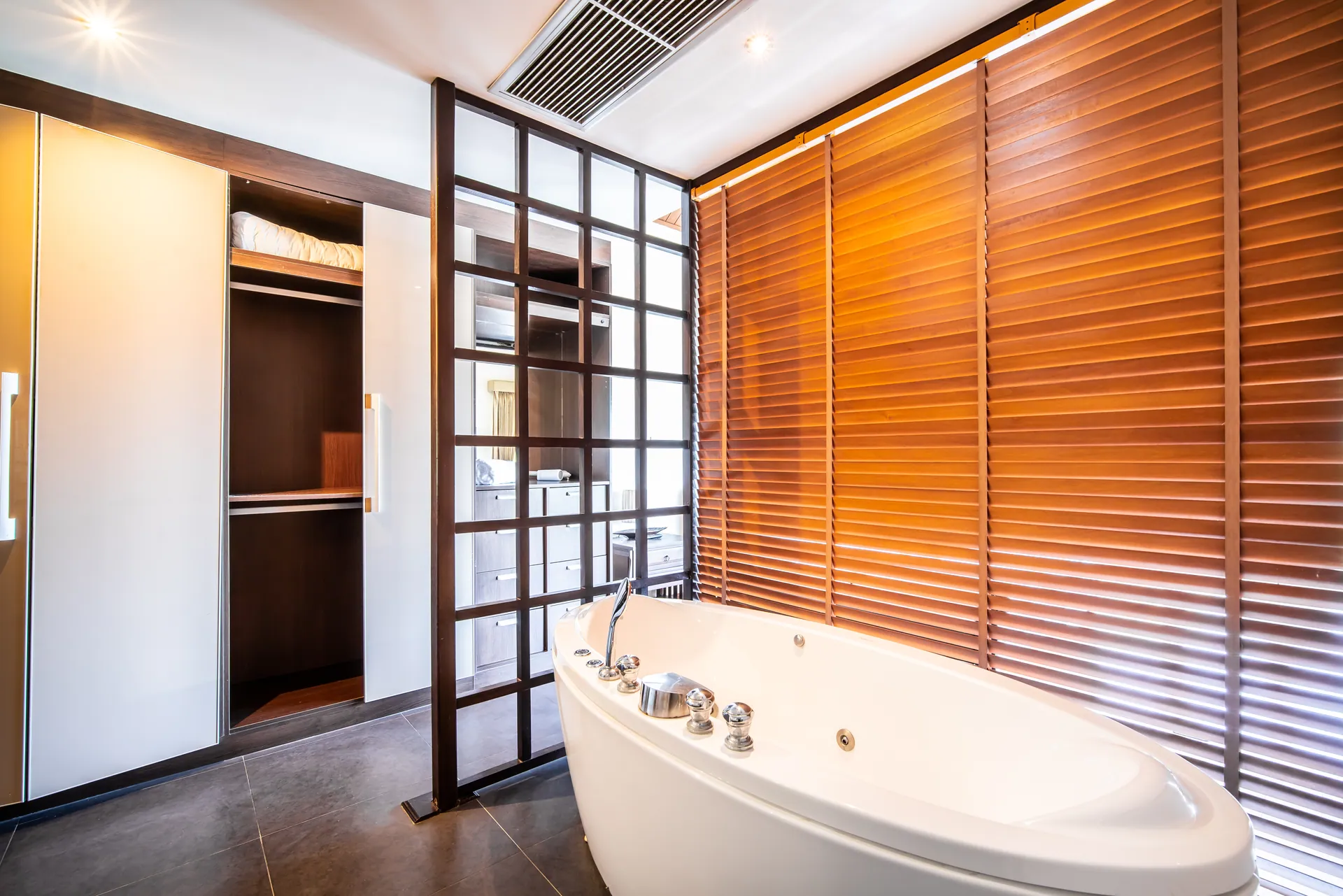 Bedroom 2 bathroom with a whirlpool bath beside timber blinds and a walk-in wardrobe
