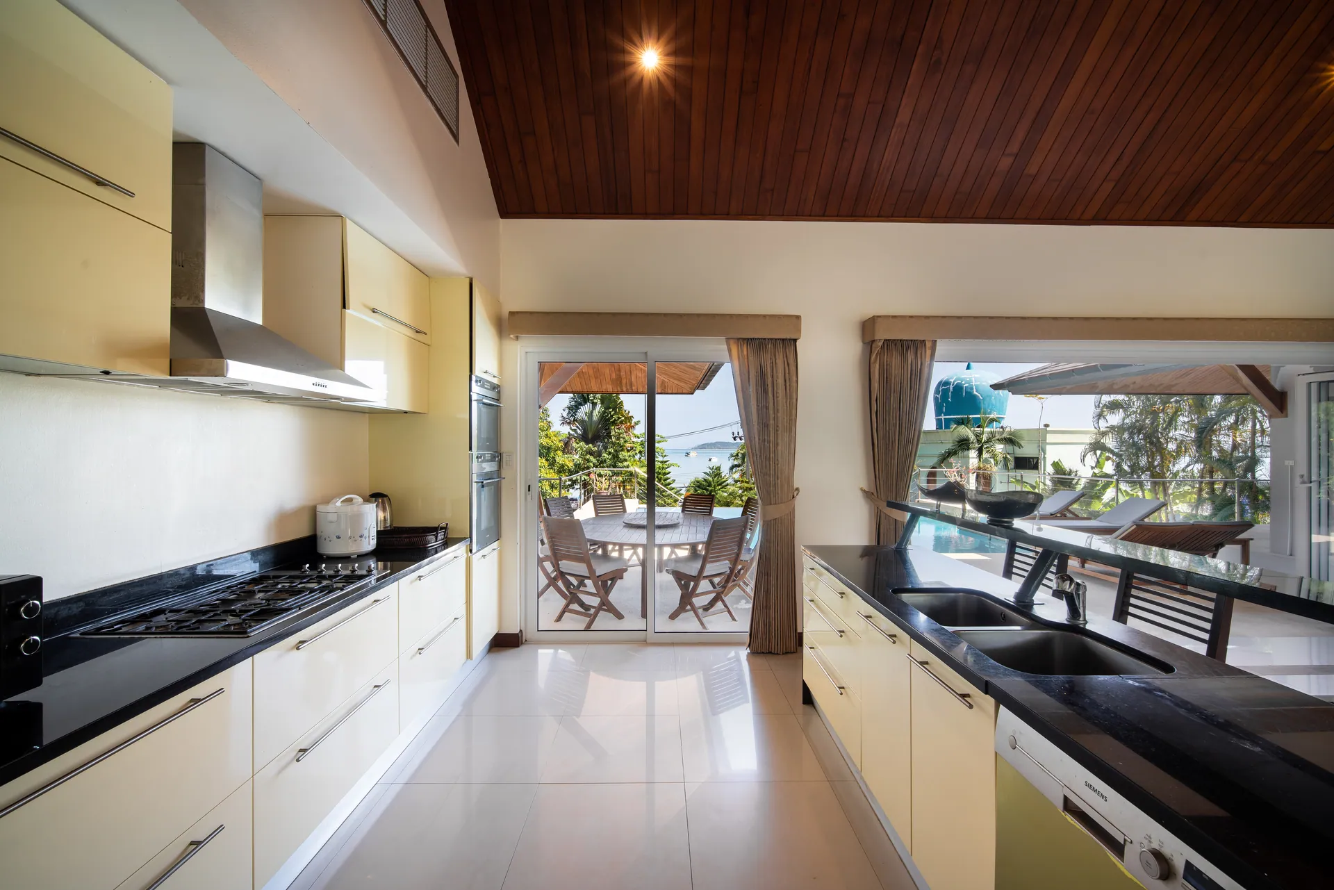Kitchen with cream cabinetry, a gas hob and a double sink, with glass doors to the outdoor dining terrace