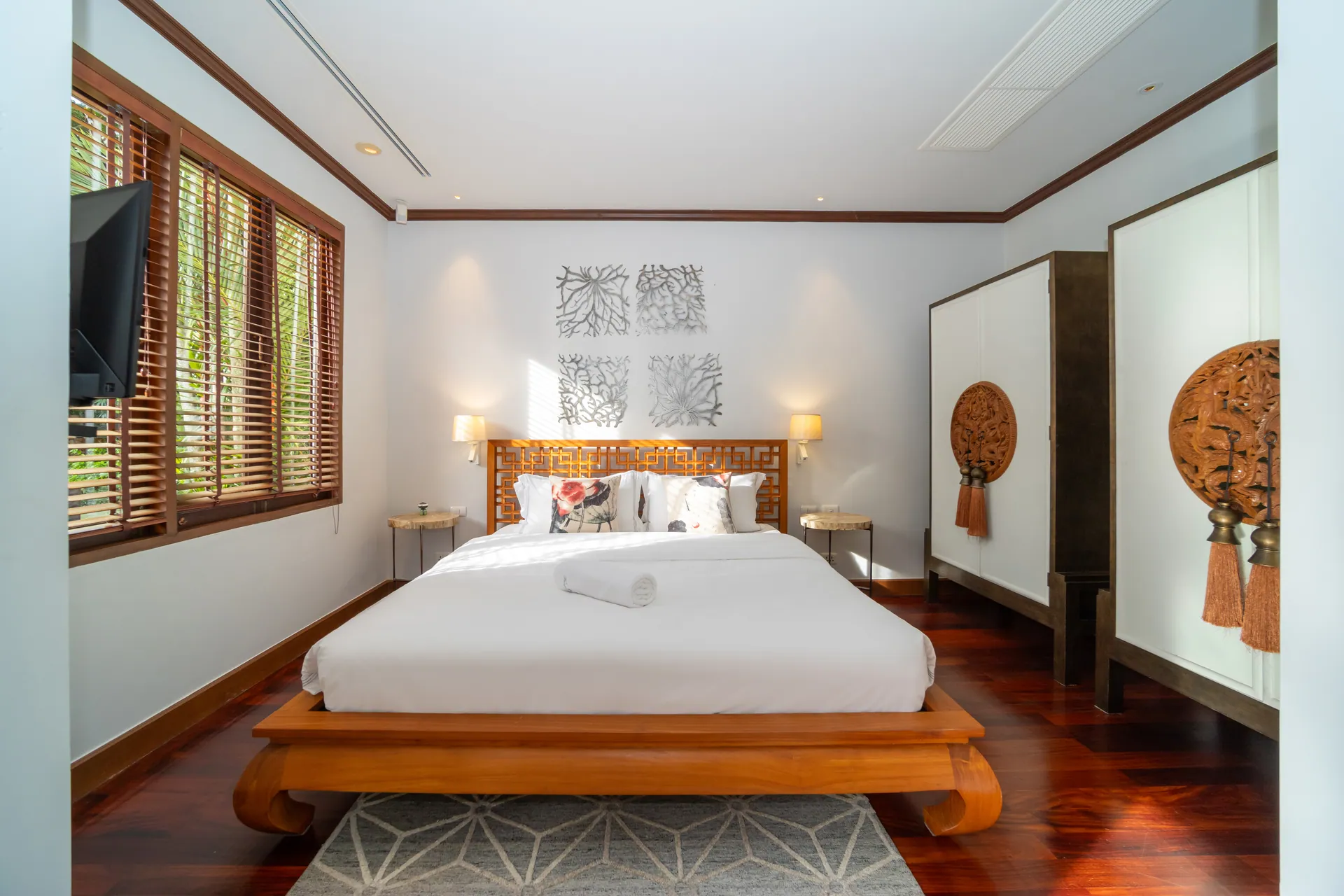 Bedroom with a large bed on a curved timber frame, a lattice headboard and carved wall medallions