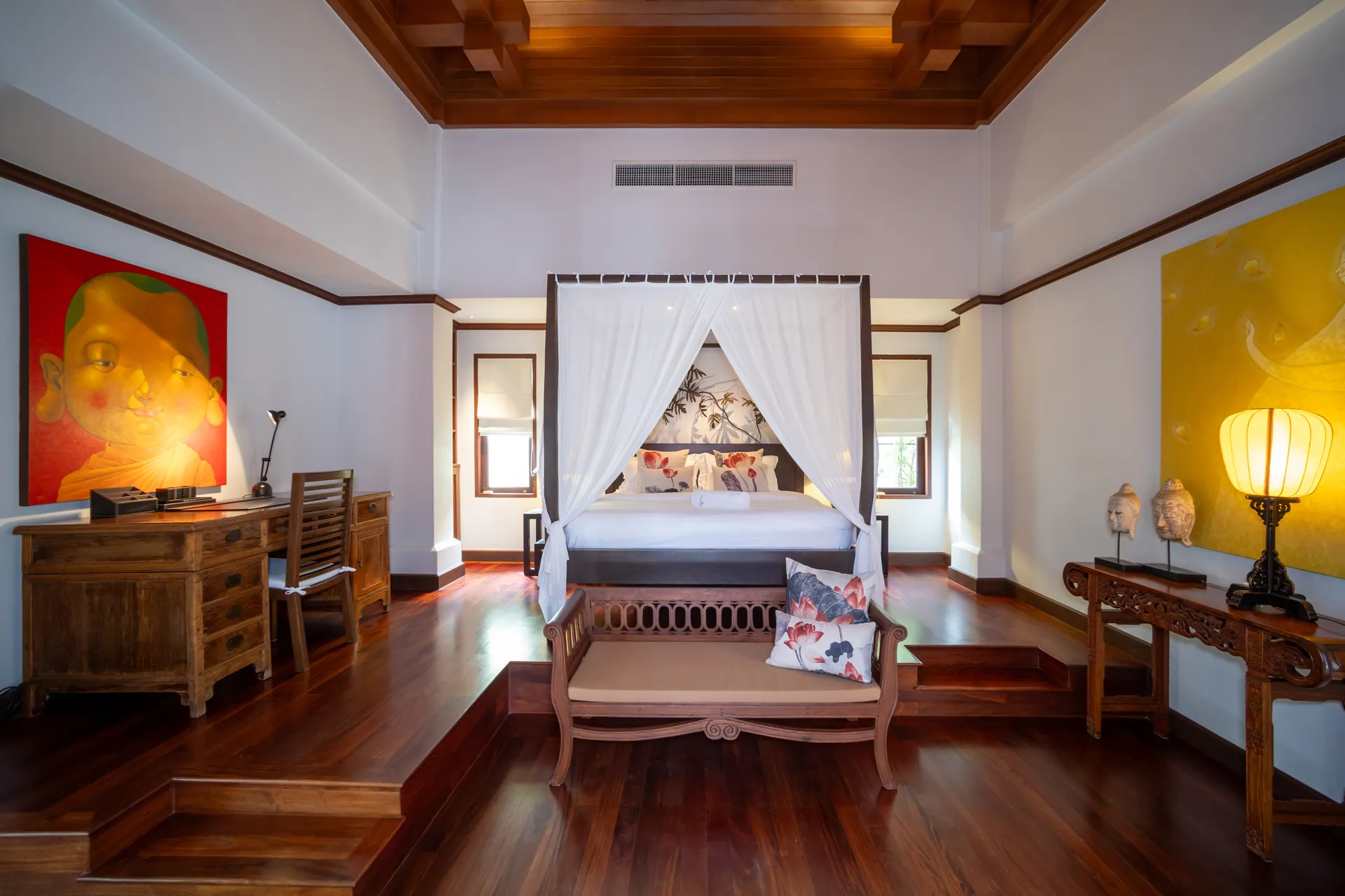 Master bedroom with a four-poster canopy bed on a raised platform, under a carved timber ceiling