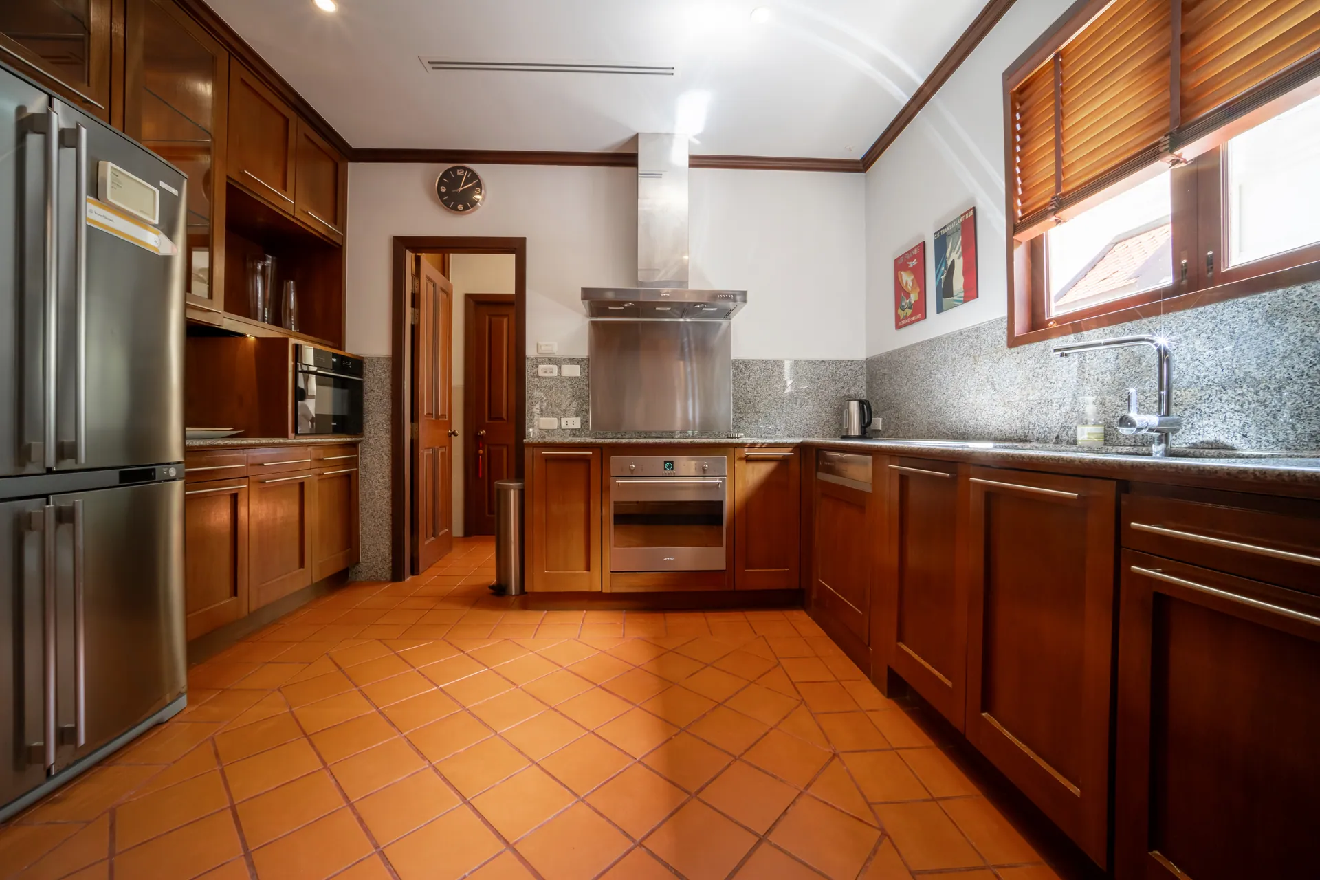 Fitted kitchen with timber cabinetry, a double-door refrigerator, a built-in oven and terracotta floor tiles