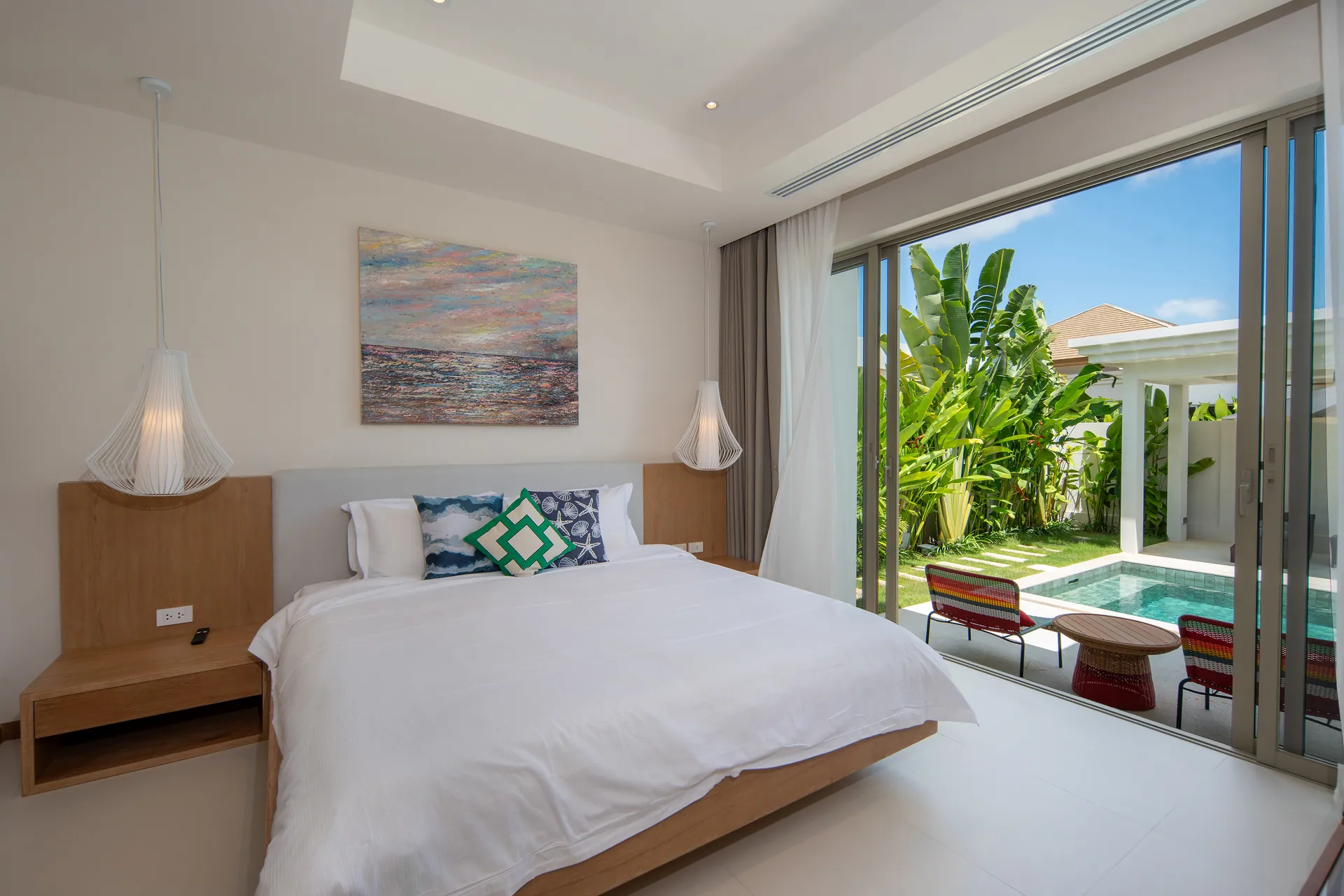 Main bedroom with sliding glass doors onto the pool terrace and pendant lights either side of the bed