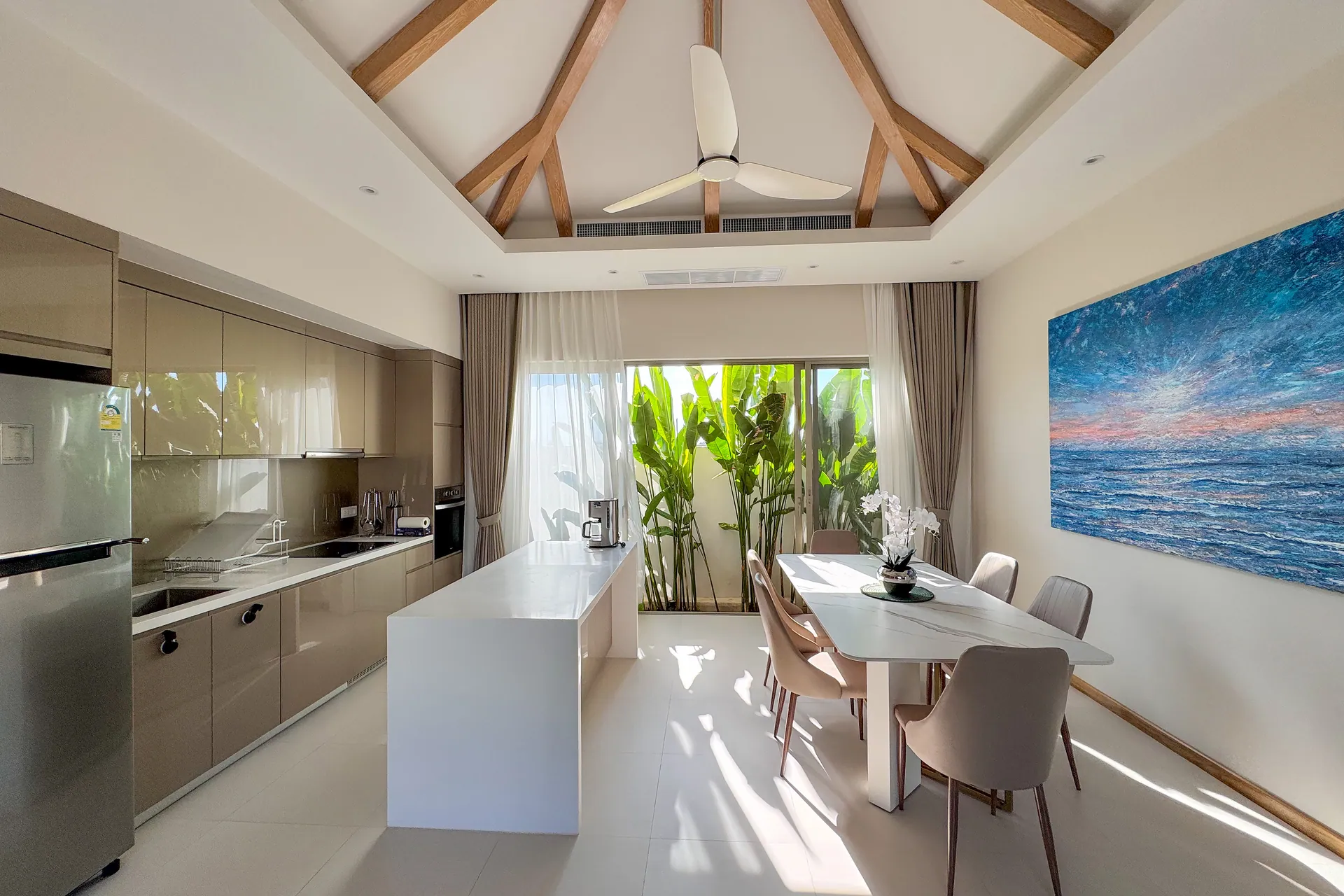 Kitchen with a white island and full-height units, beside a dining table under an ocean painting