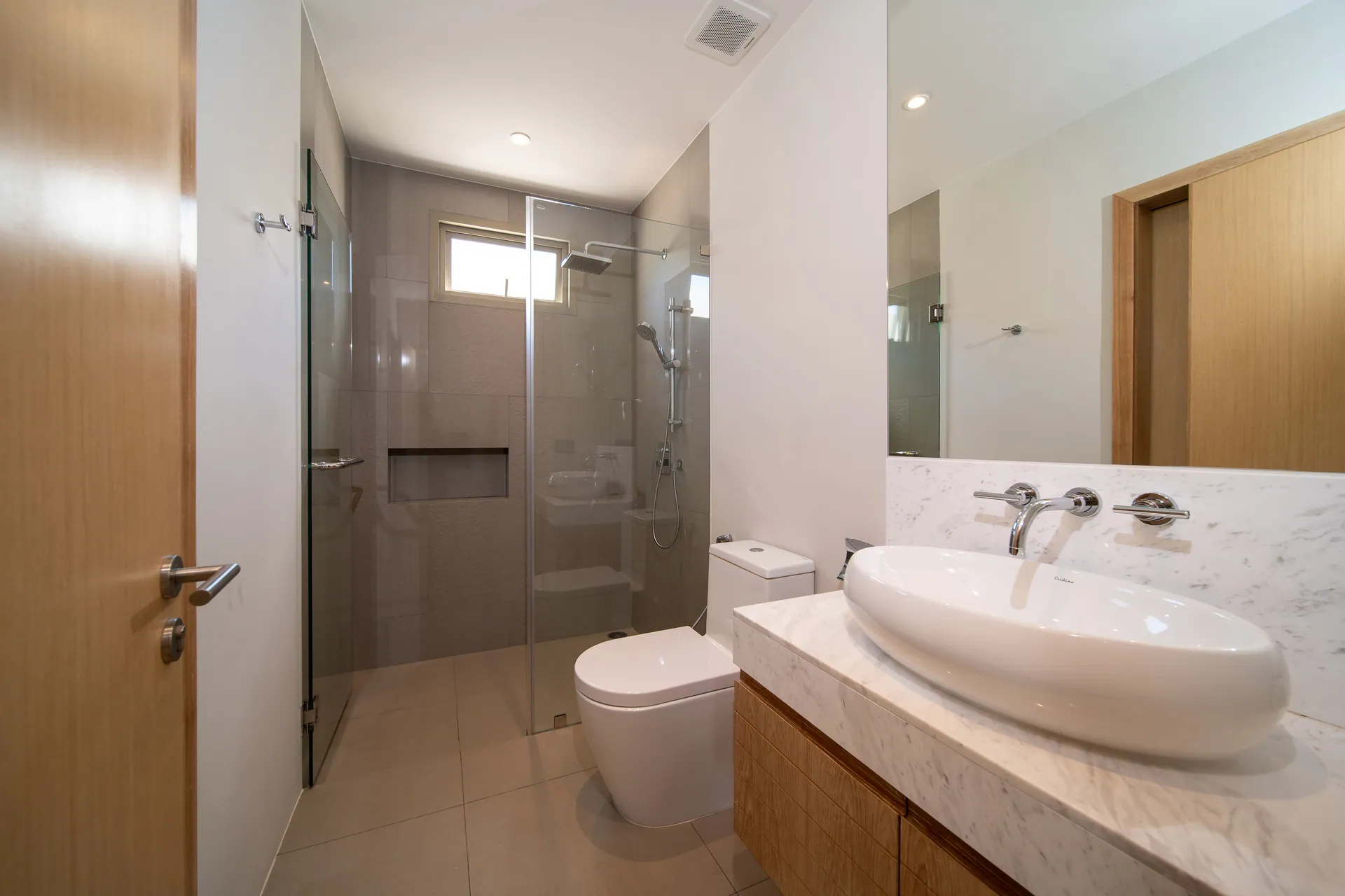 Bathroom with a vessel basin on a marble counter and a walk-in rain shower