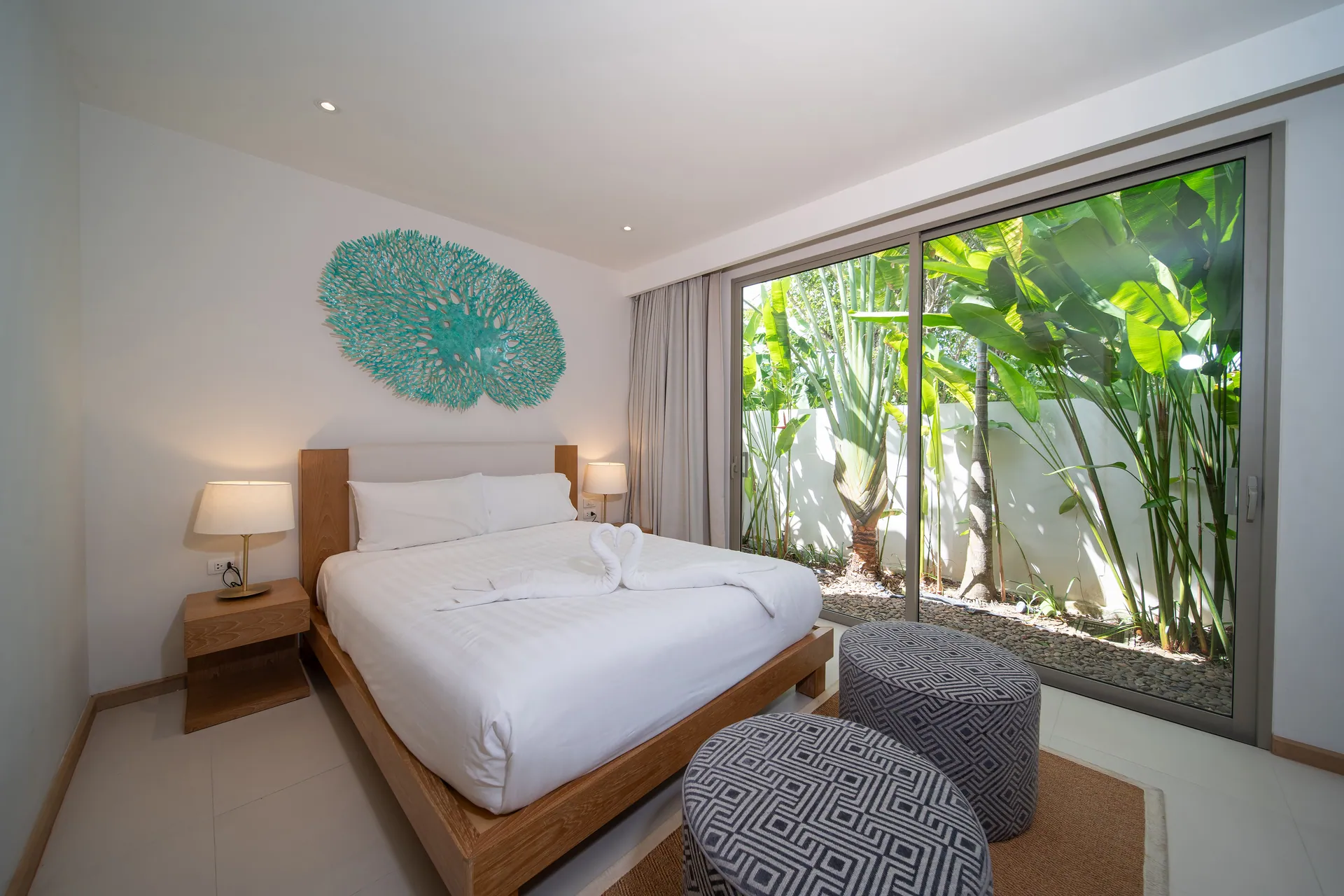 Bedroom with a coral wall motif and full-height glass onto a planted courtyard