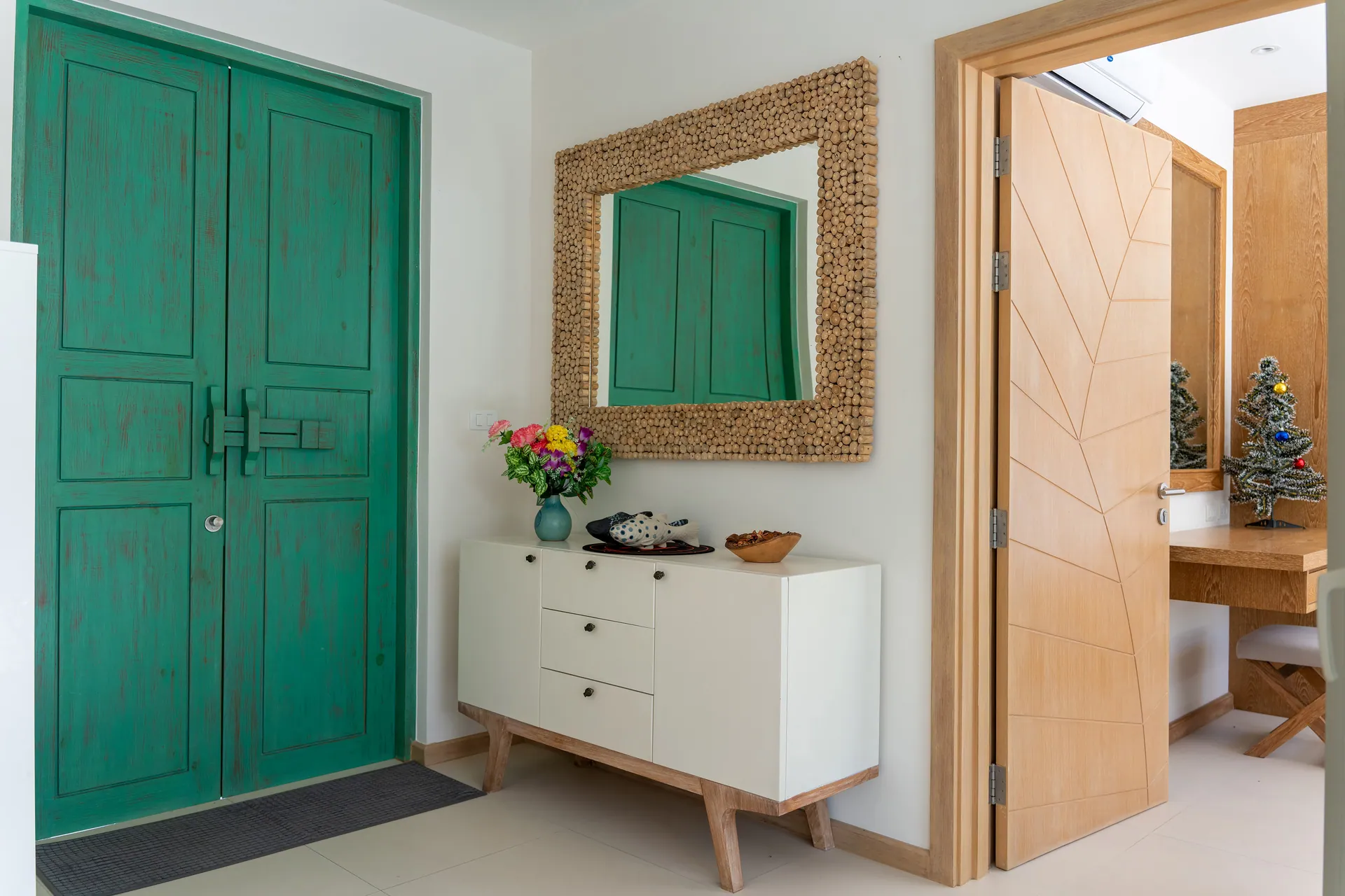 Entrance hall with teal double doors, a textured mirror and a white sideboard