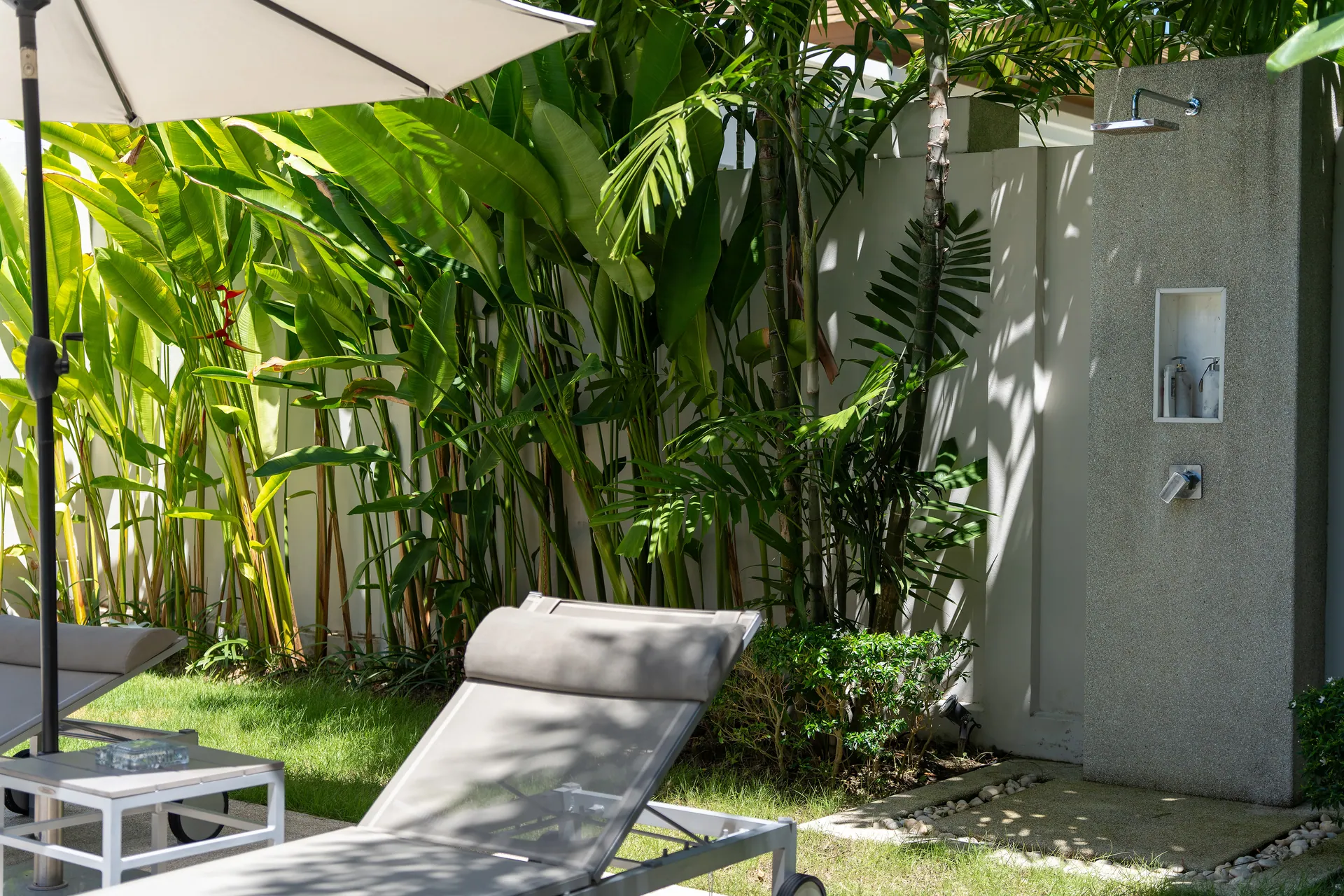 Sun lounger beside an outdoor shower in the tropical garden