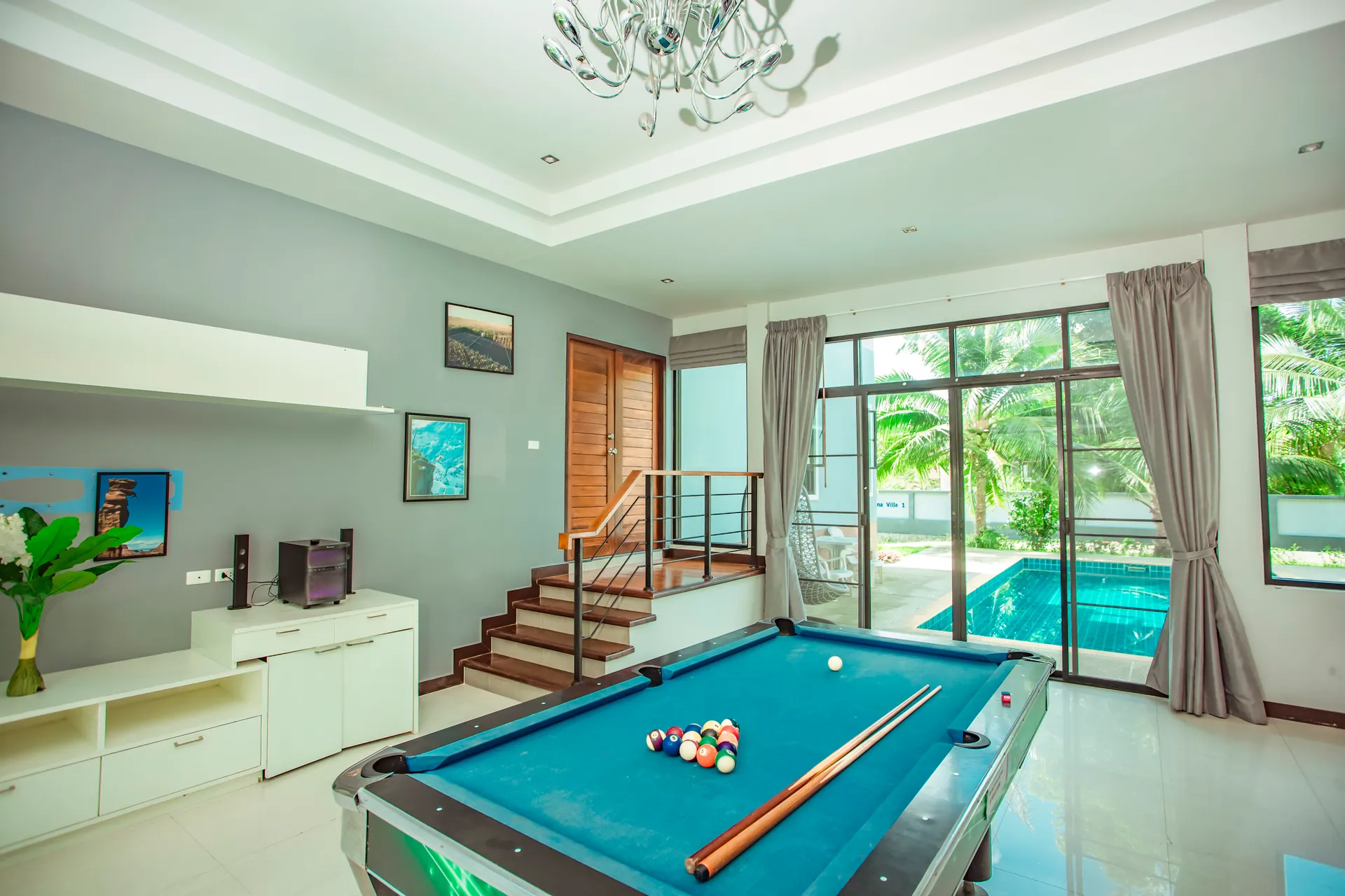 Games room with a pool table and a TV unit, with glass doors opening onto the pool
