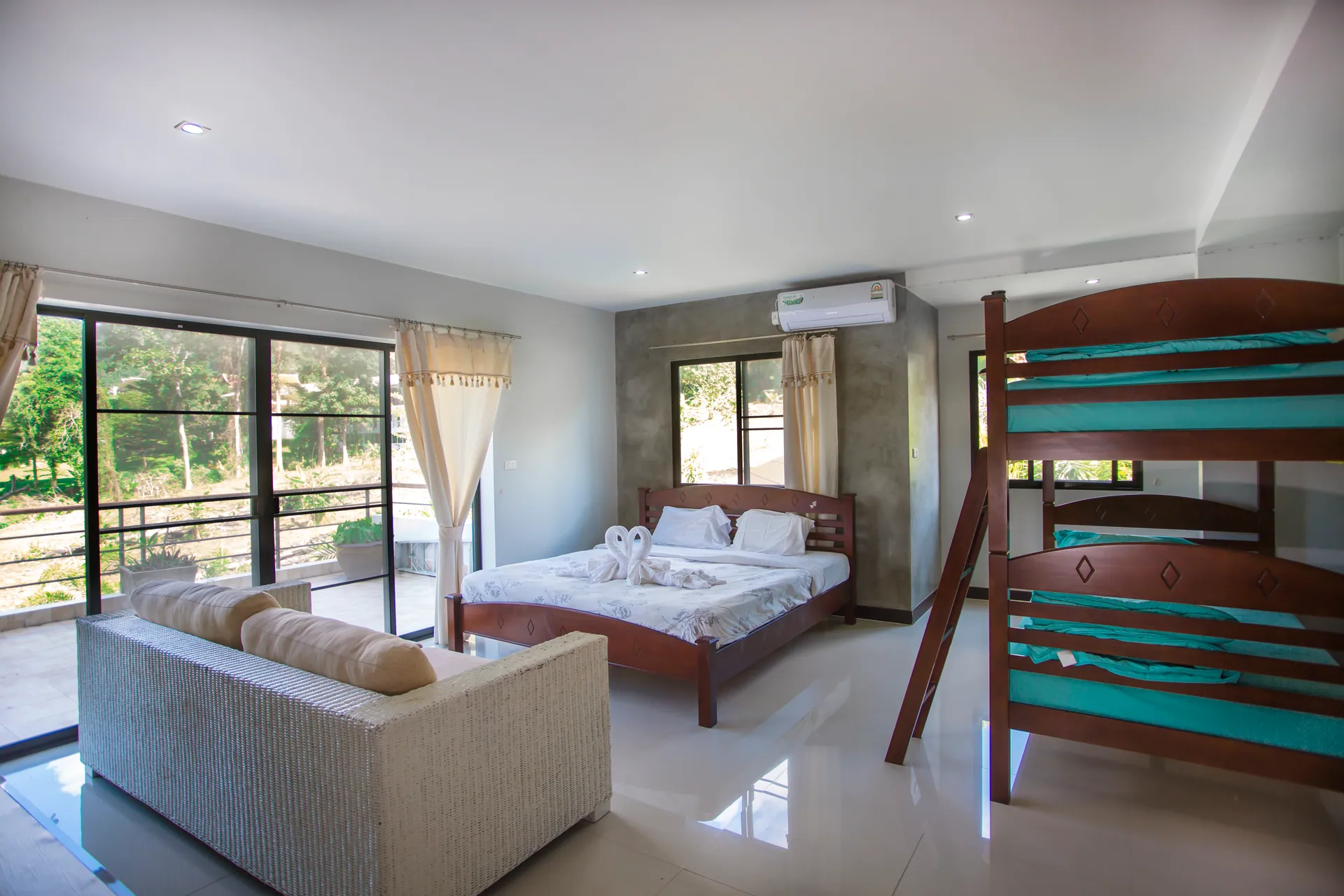 Family room with a double bed, a bunk bed and a sofa, with glass doors to a balcony