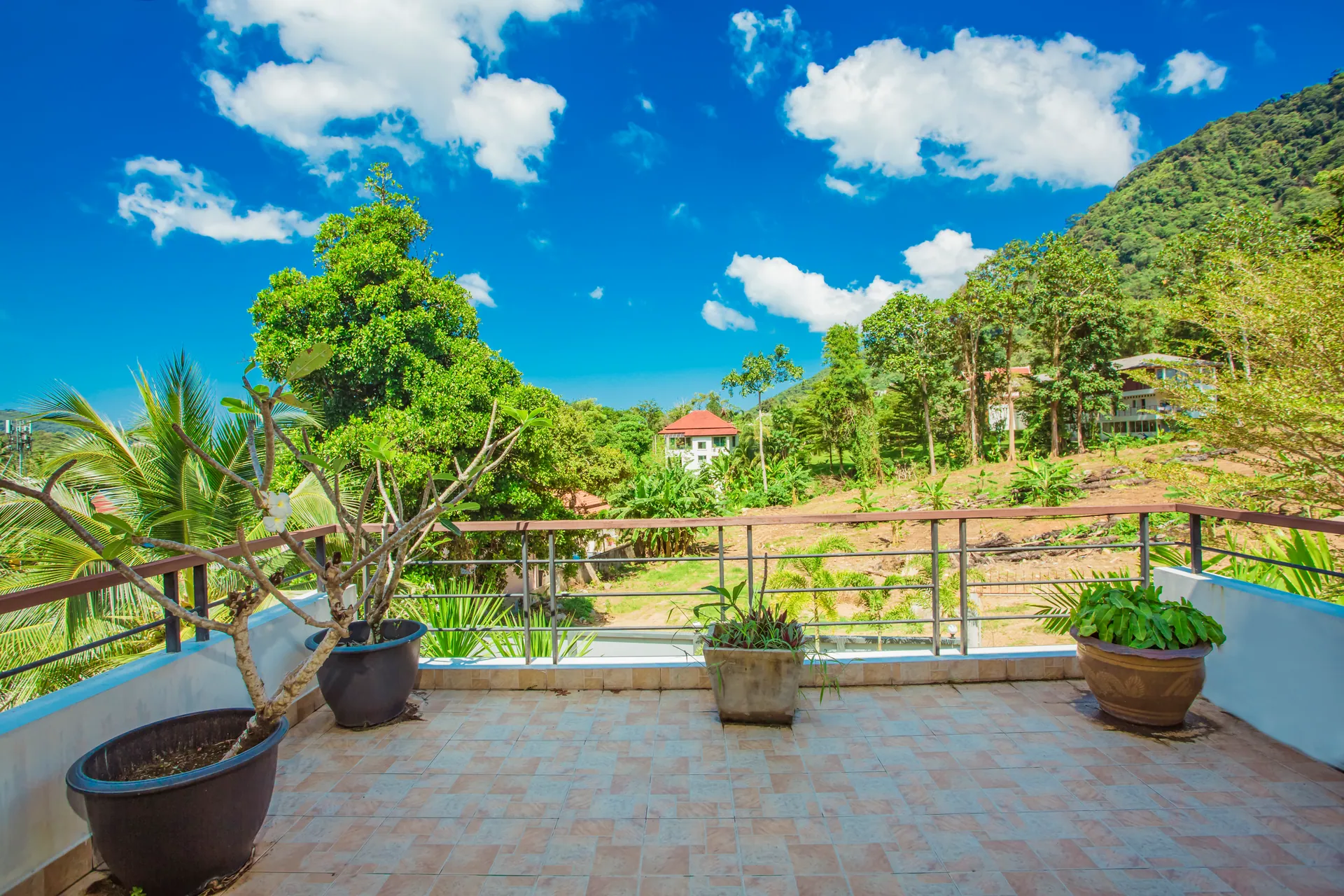 Tiled upstairs terrace with potted plants, looking out to the wooded hills