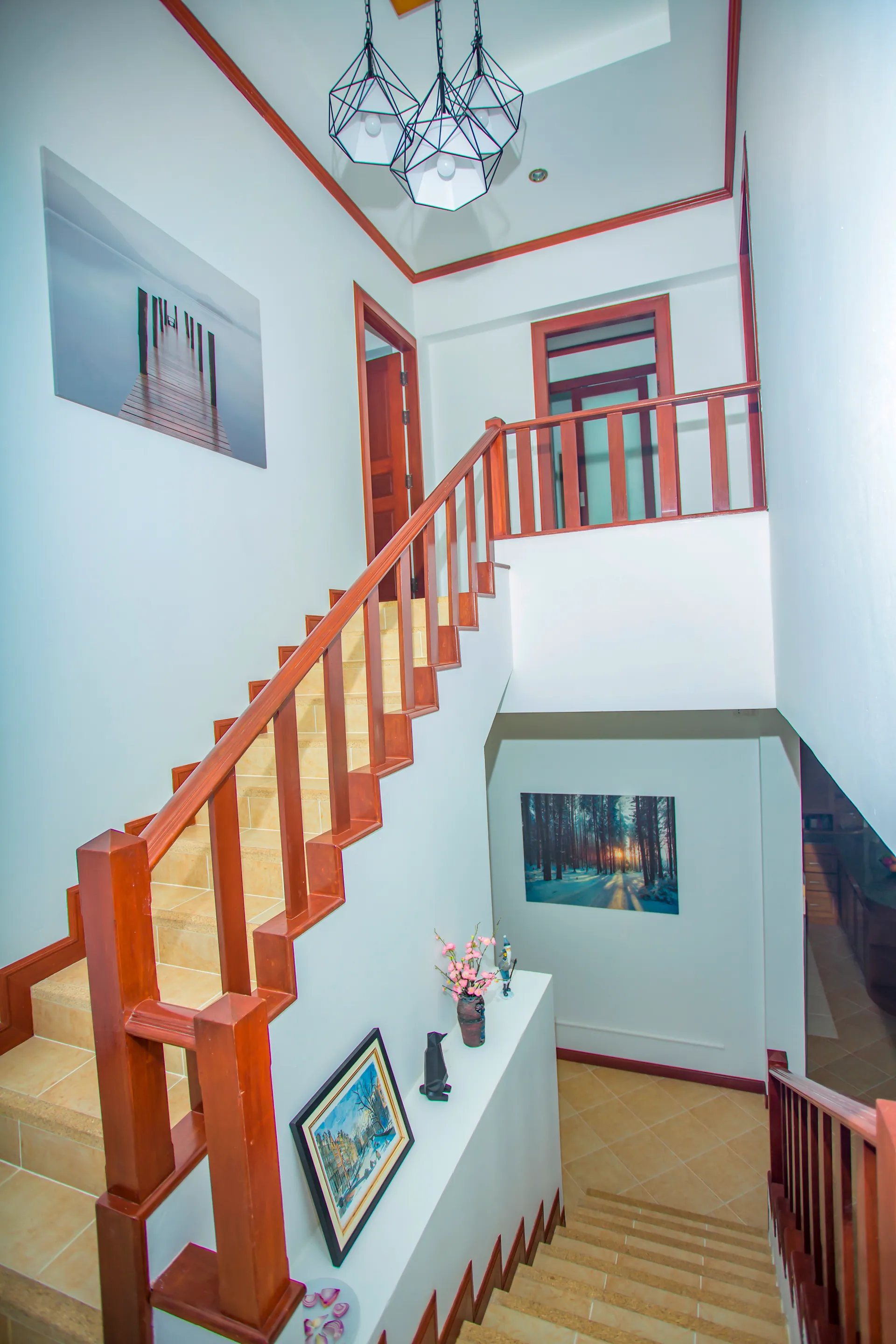 Staircase with a polished timber handrail rising to the upper floor below a geometric pendant light