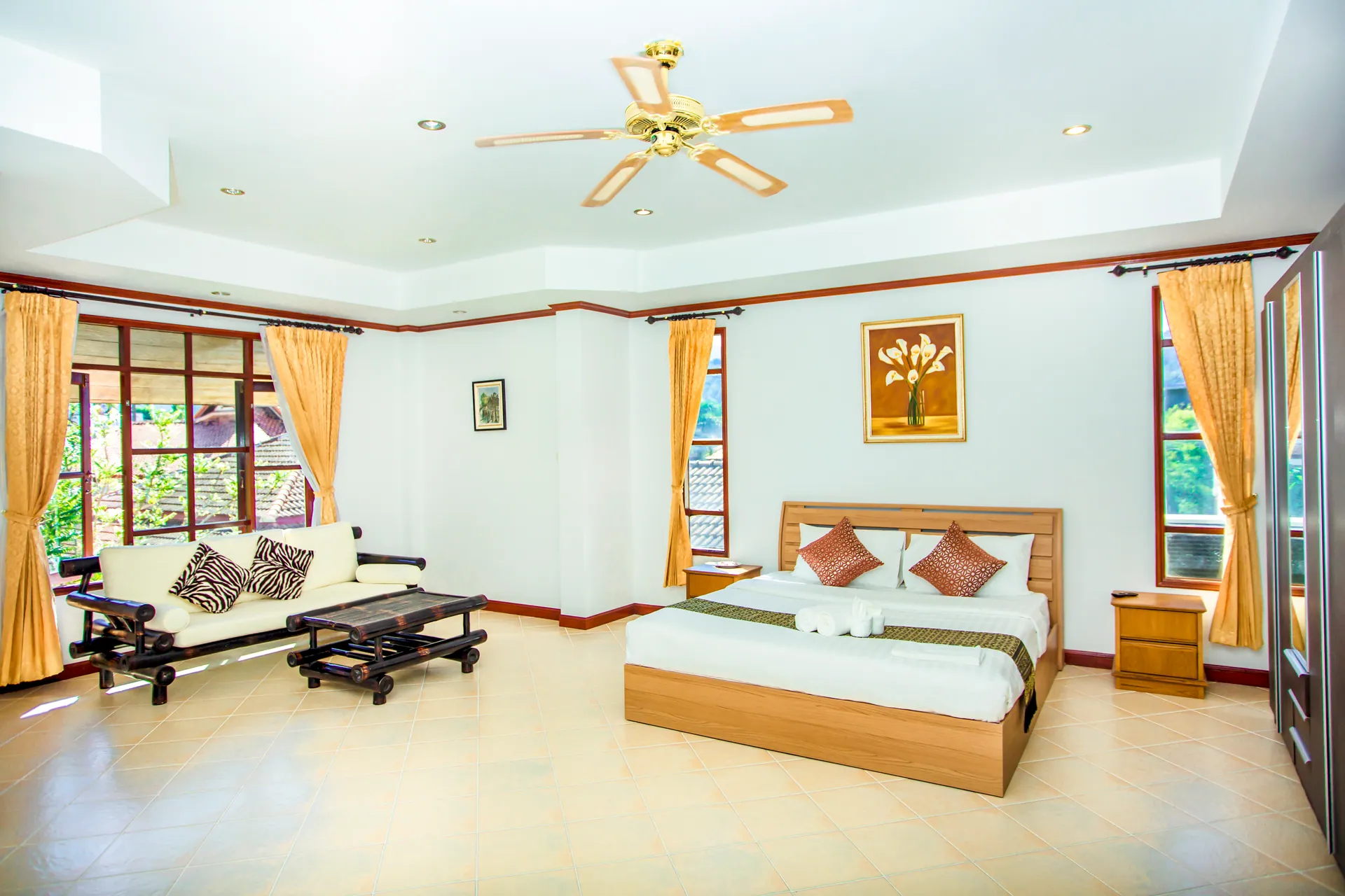 Bedroom with a double bed, a sitting area with a sofa and low table, and a ceiling fan