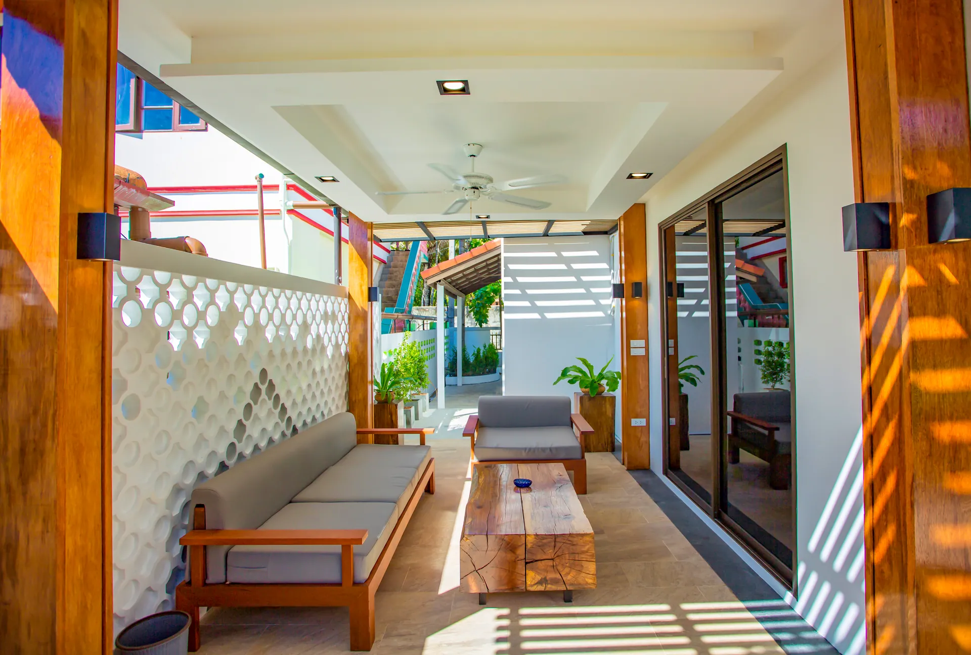 Covered terrace with a timber-framed sofa, a solid-wood coffee table and a white lattice screen