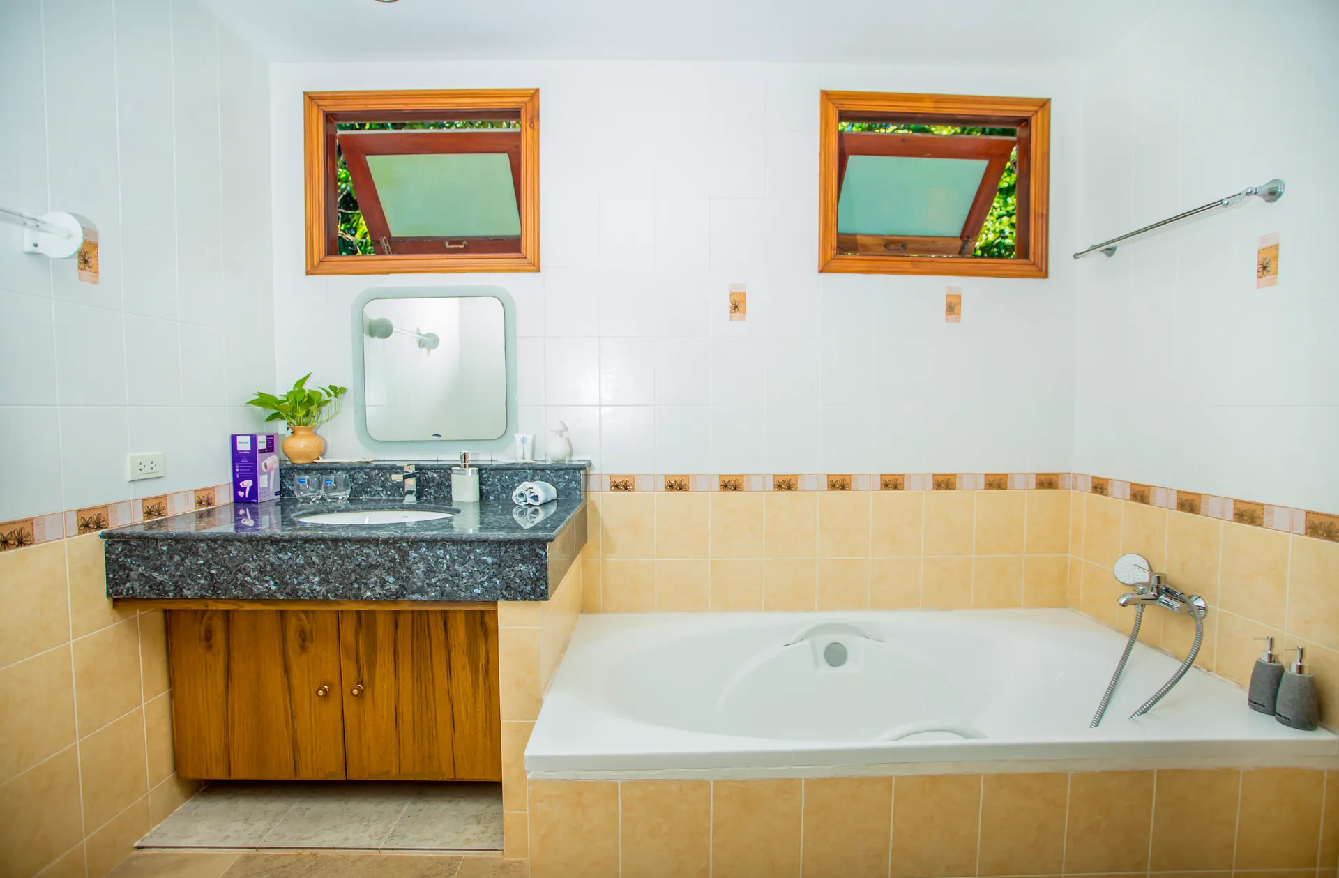 Bathroom with a built-in bathtub, a granite vanity and high timber-framed windows