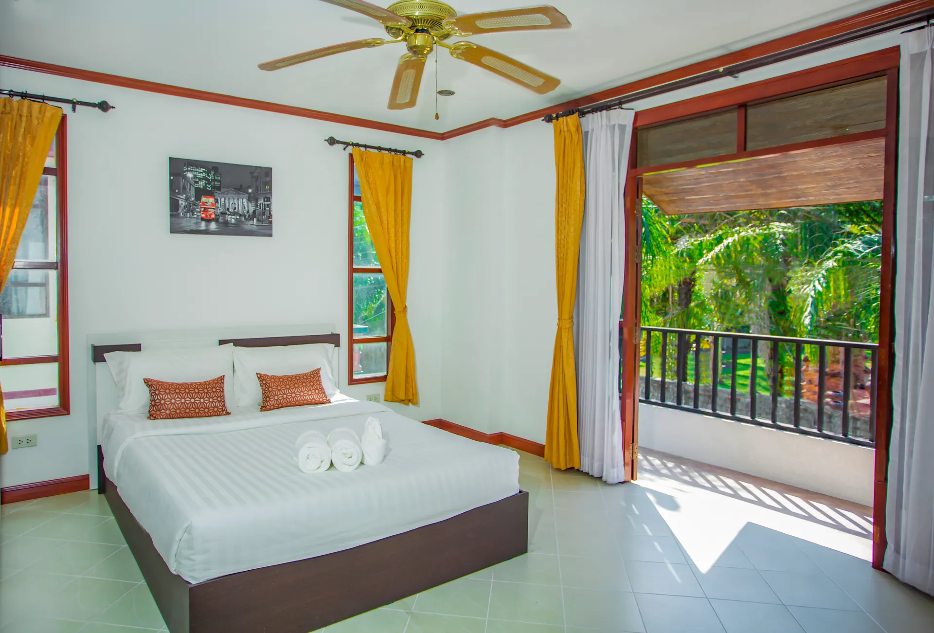 Bedroom with a double bed and a ceiling fan, its glass door open onto a balcony facing the trees