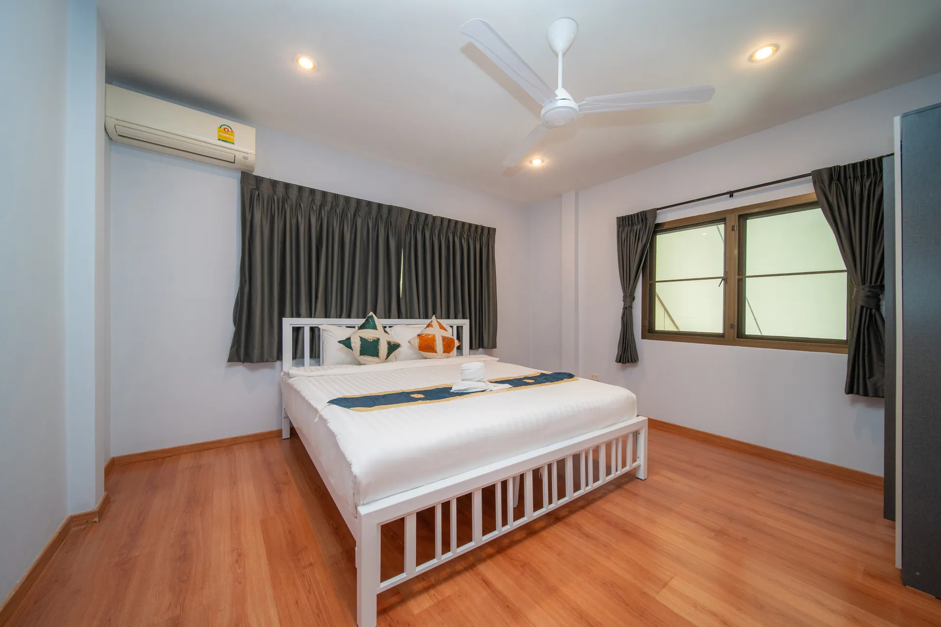 Bedroom with windows on two walls, a ceiling fan and air conditioning