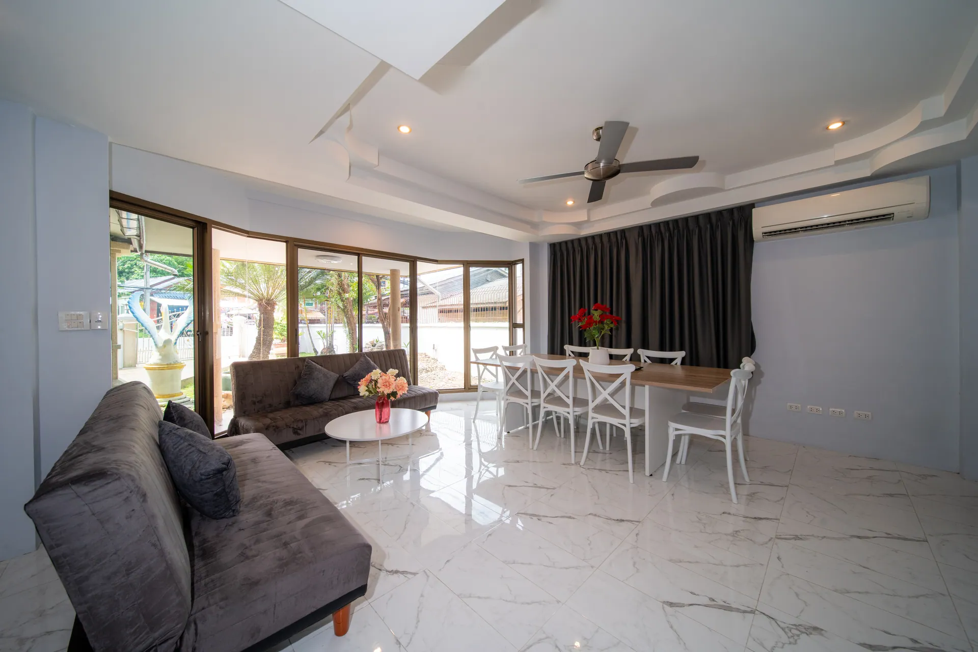 Living room with grey sofas, a marble-effect floor and sliding glass doors to the garden