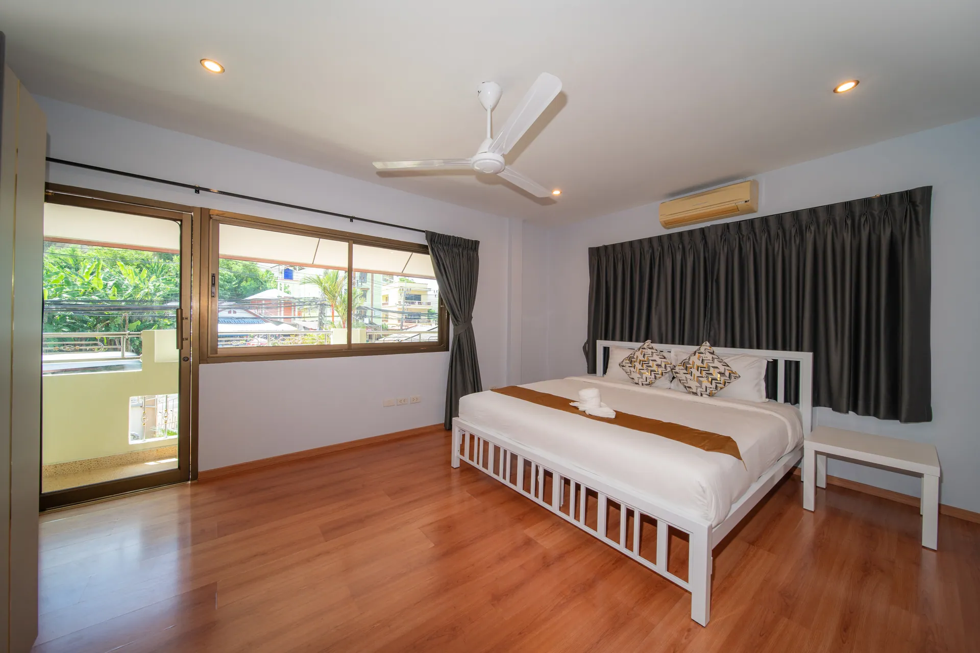 Bedroom with sliding doors to a balcony and a large bed with a gold runner