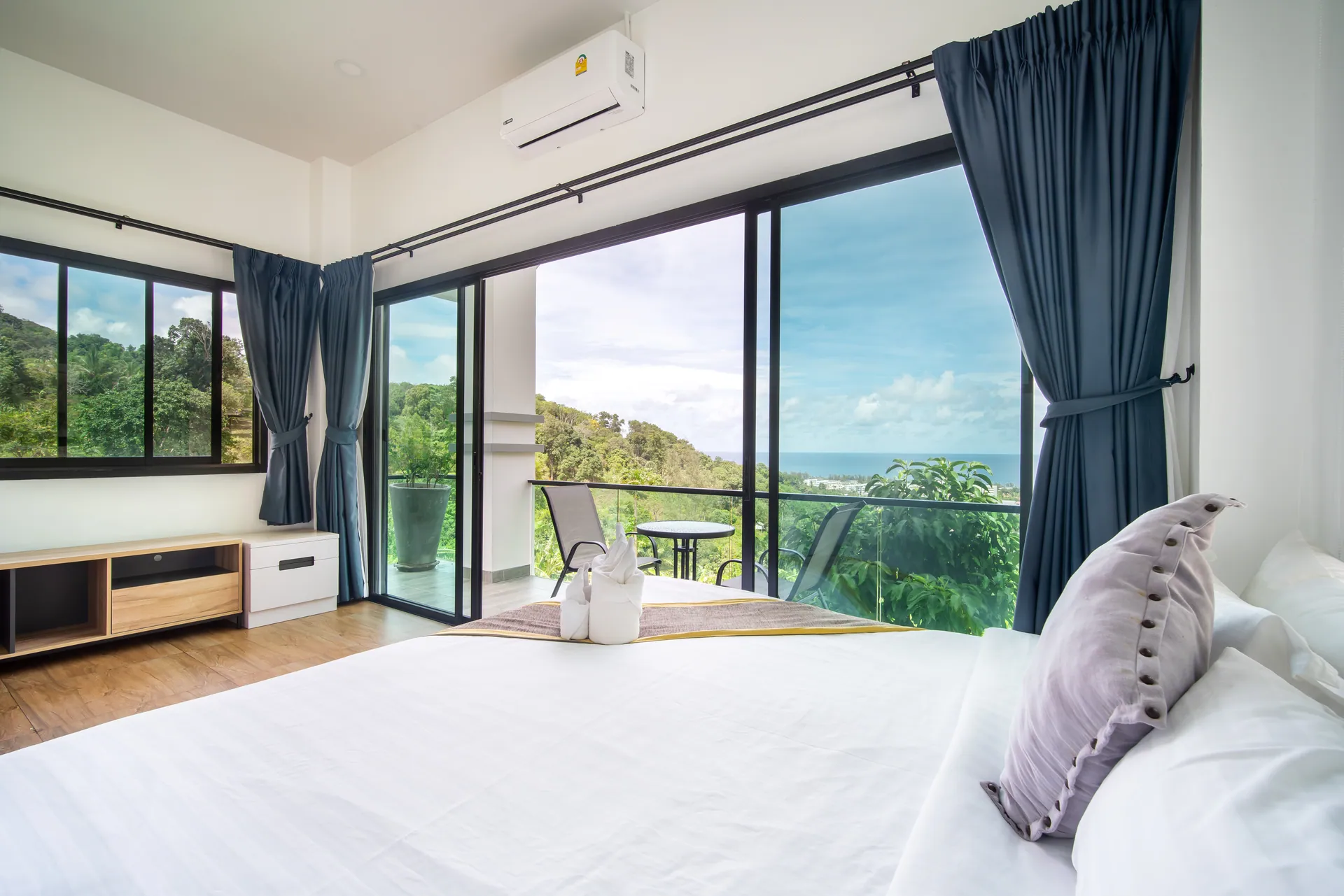 Bedroom with a double bed and full-height glass doors opening to a balcony with a sea view