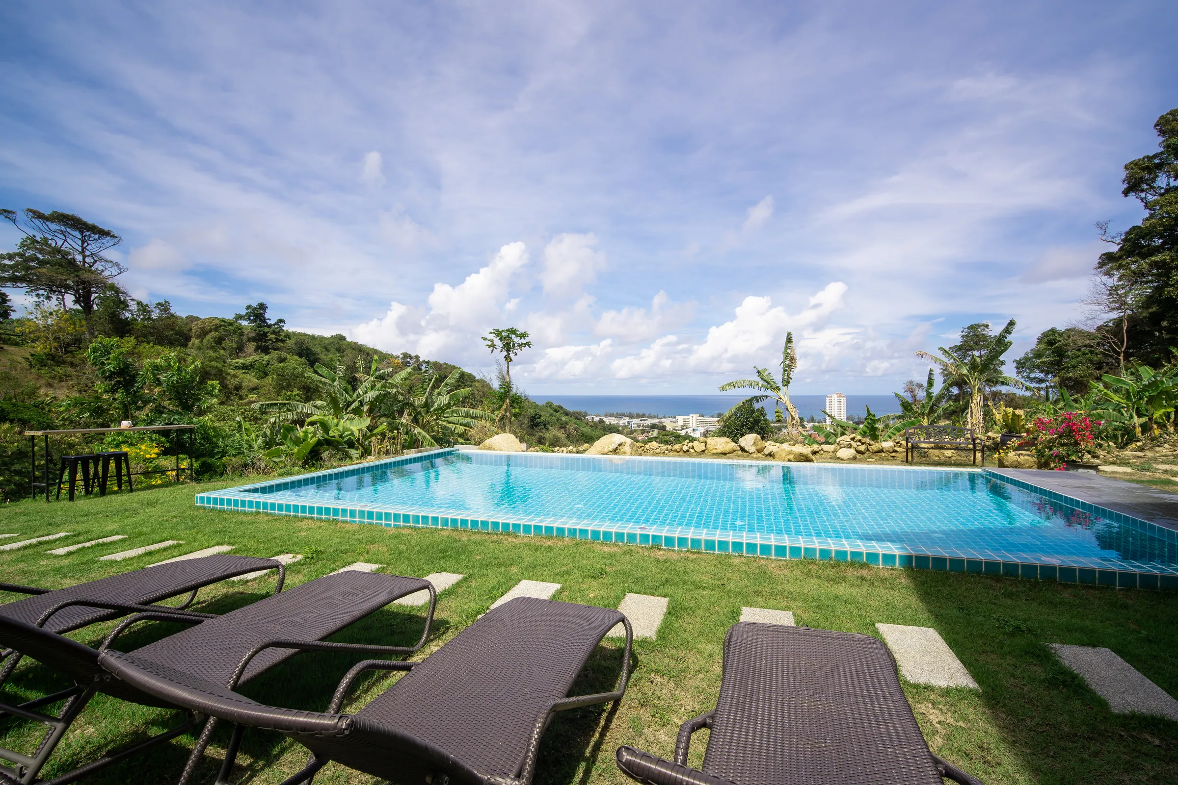 Private pool on a lawned terrace with sun loungers, looking across the hillside to the sea