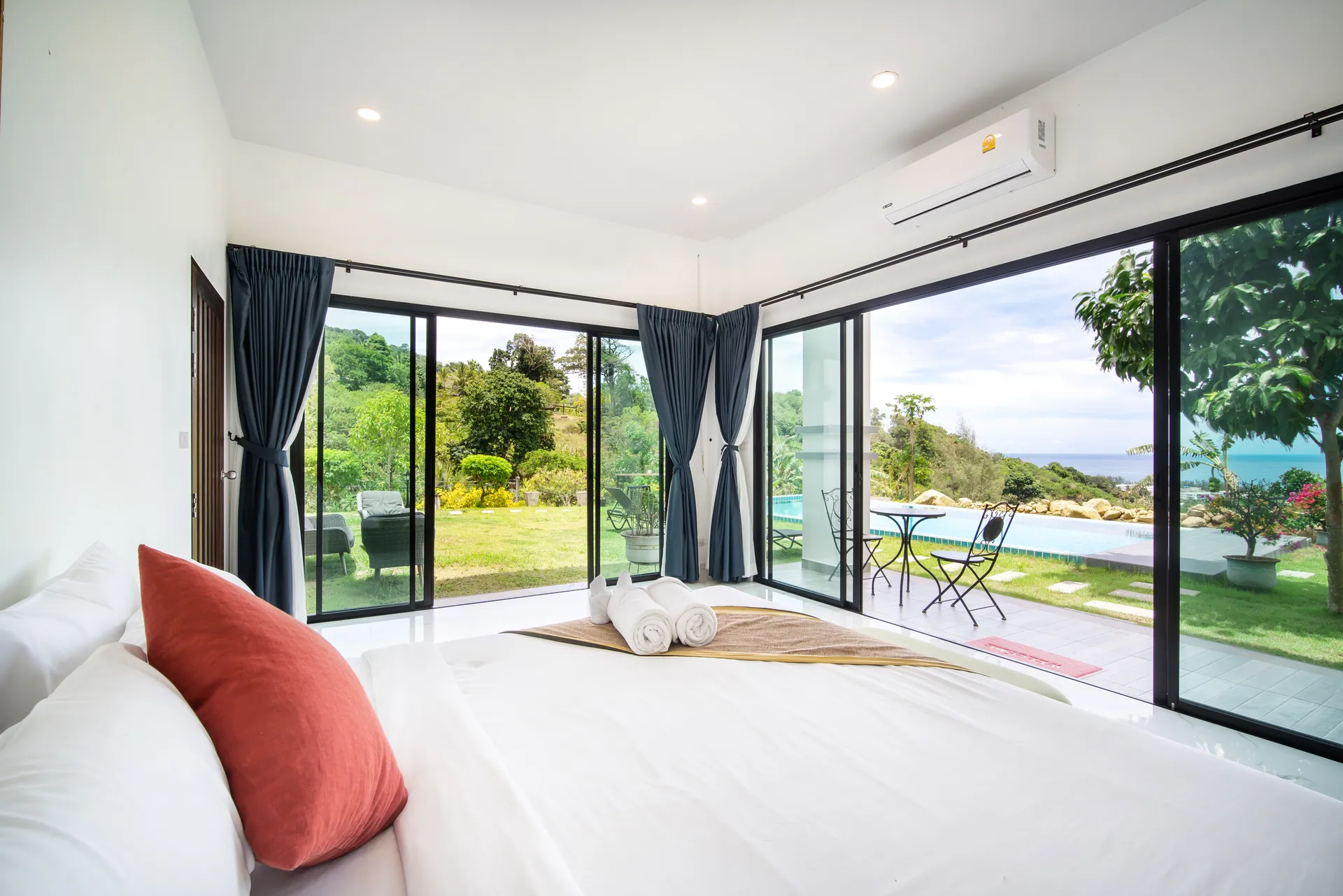 Ground-floor bedroom with glass doors on two sides, opening to the pool terrace and garden