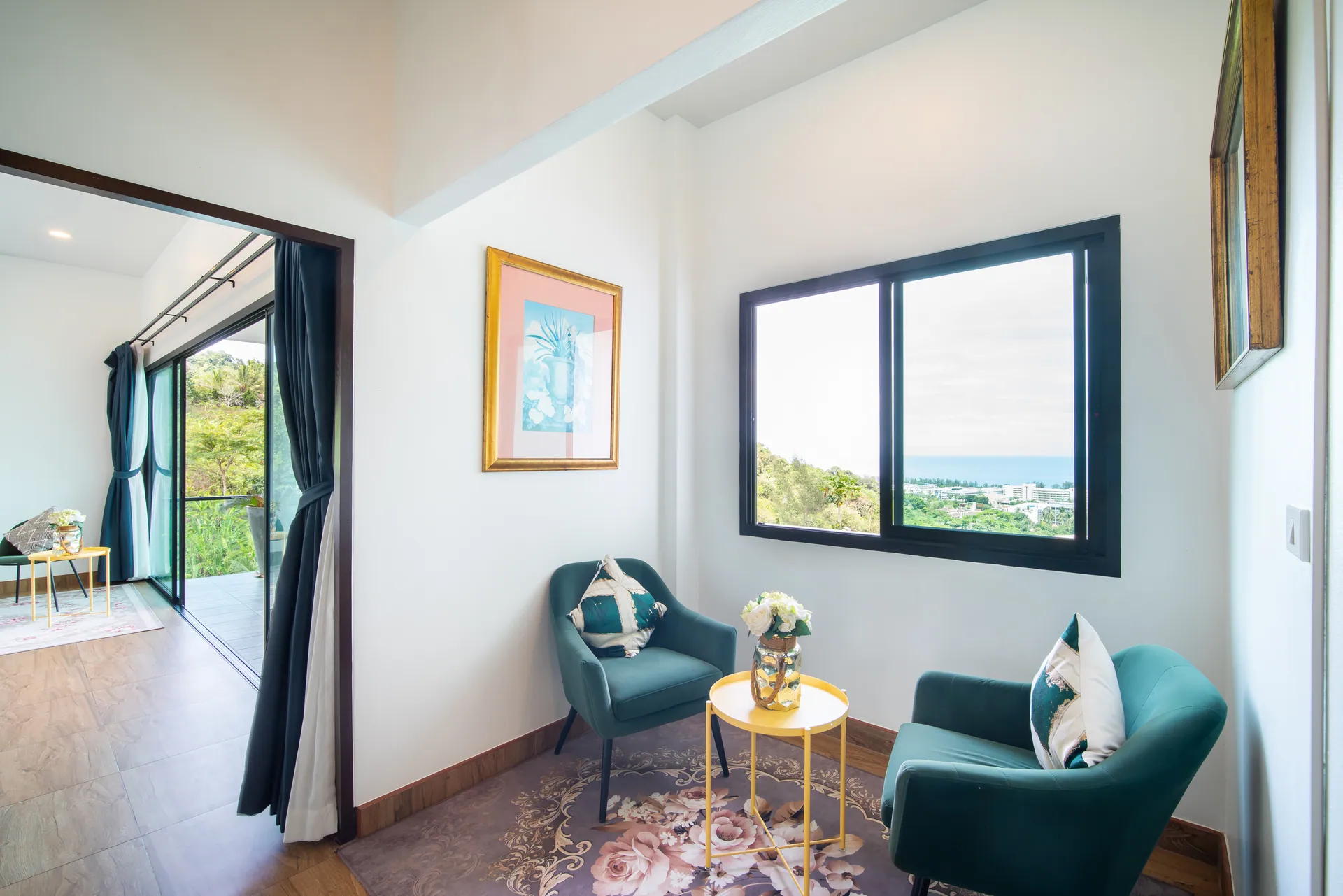 Upstairs sitting area with two teal armchairs and a window looking out to the sea