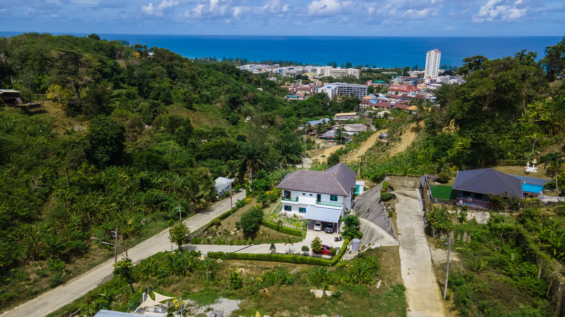 Aerial view from above the villa, down a green valley to the town and the sea