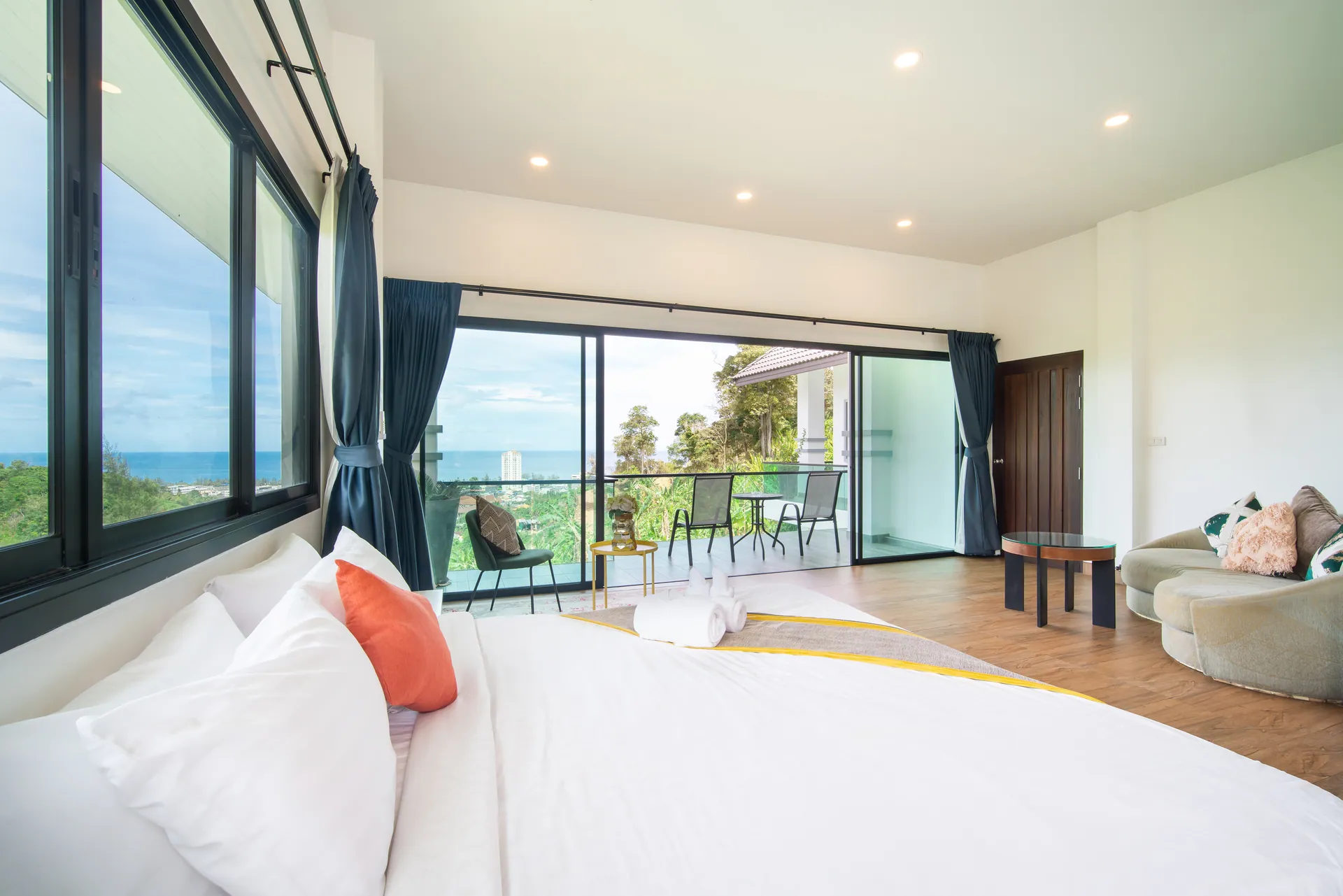Large bedroom with a double bed, a sofa and sliding doors to a balcony facing the sea