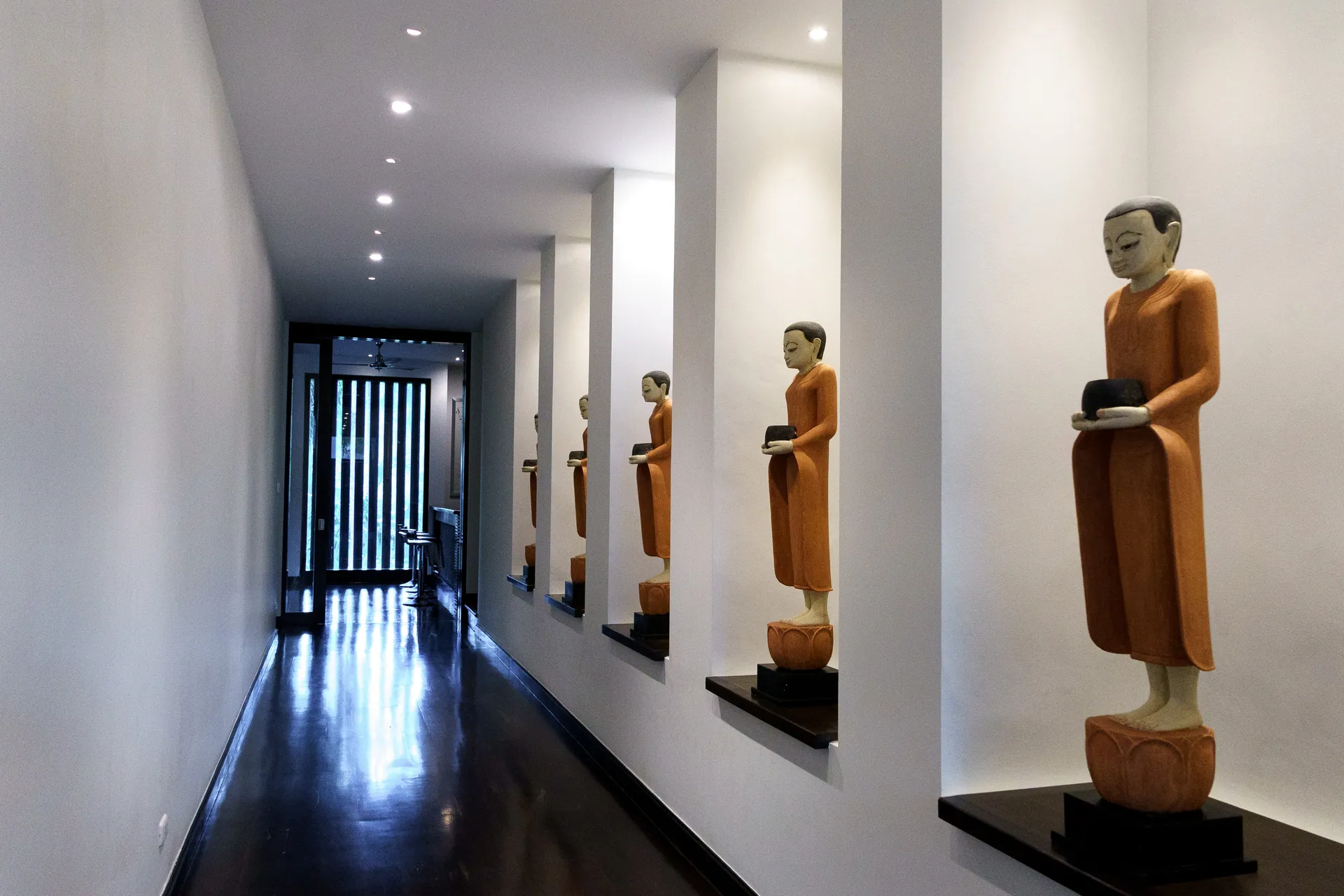Corridor lined with carved standing figures in lit wall niches