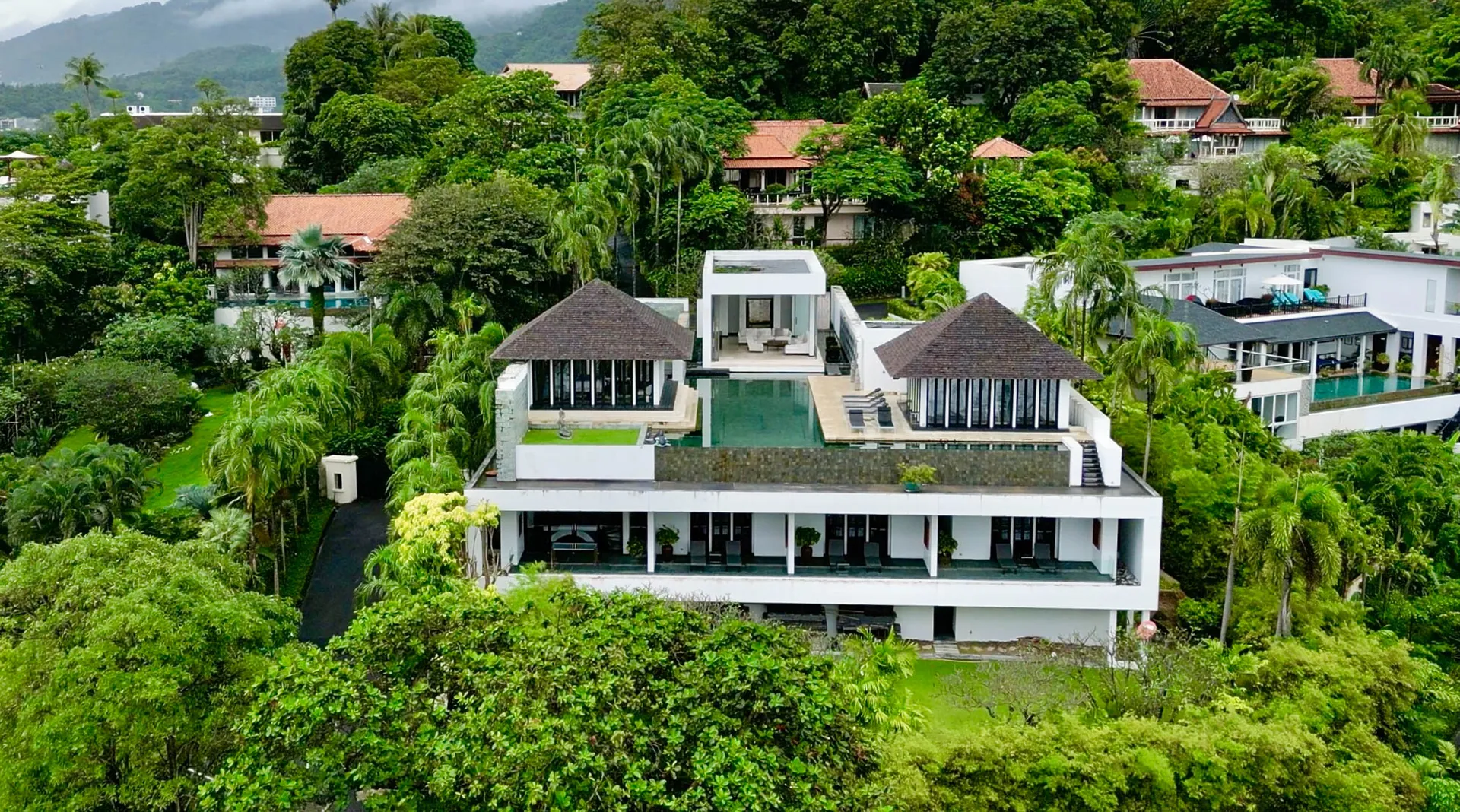 Aerial view of the villa on a wooded hillside, with two pavilions either side of the pool terrace