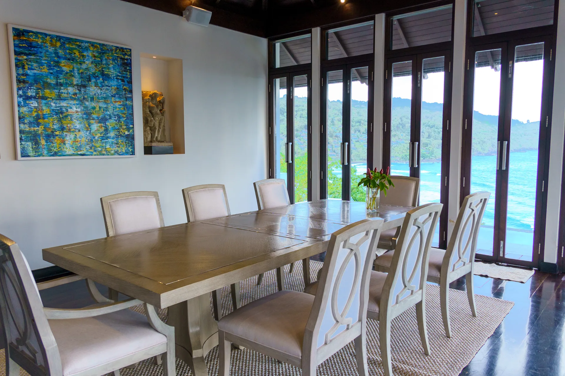 Dining table beside tall folding glass doors that look out to the bay