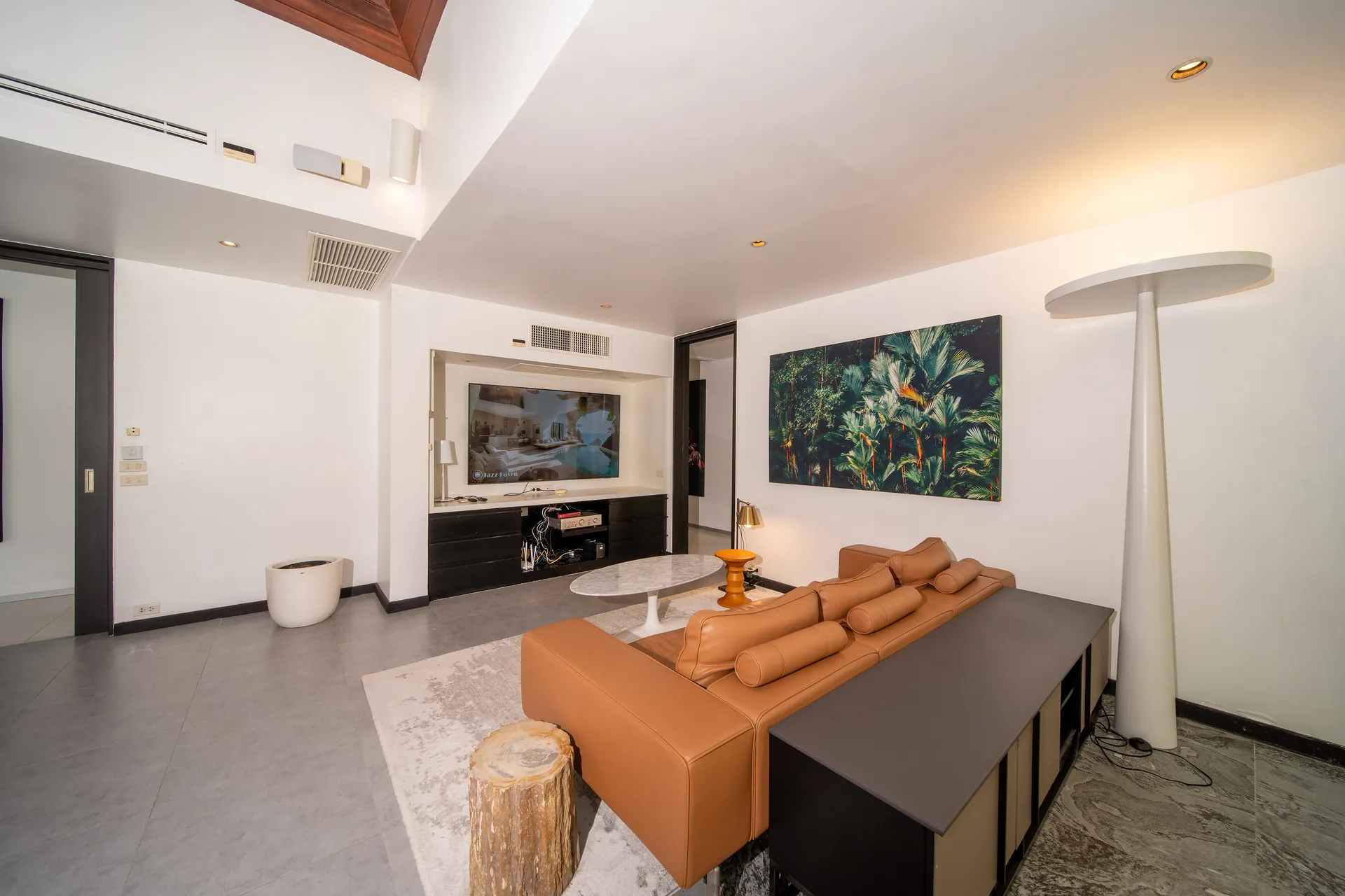 TV lounge with a leather sofa, a low media cabinet and a large botanical painting