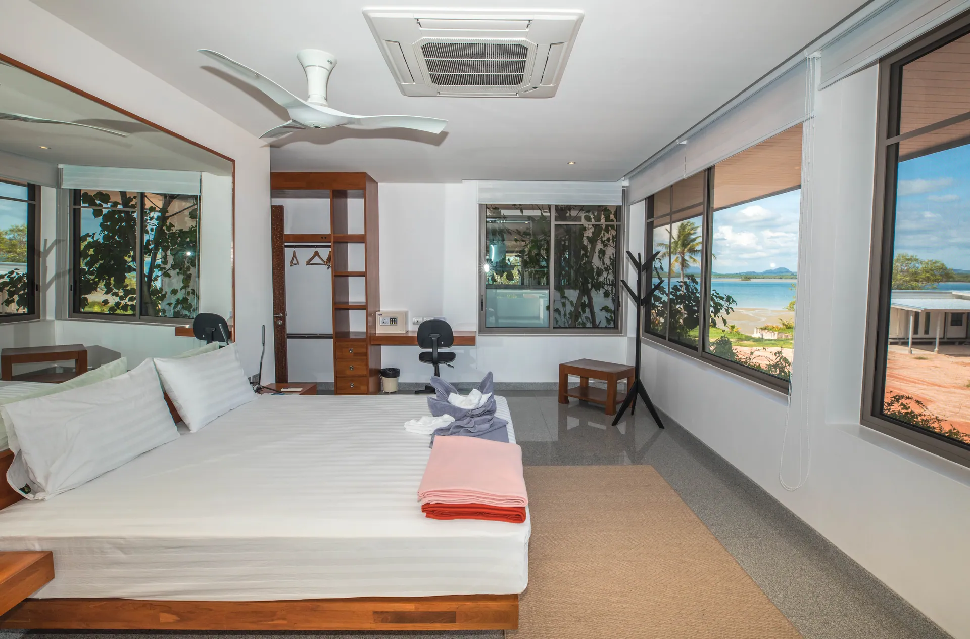 Bedroom with a platform bed, a wardrobe, a desk and corner windows looking towards the bay