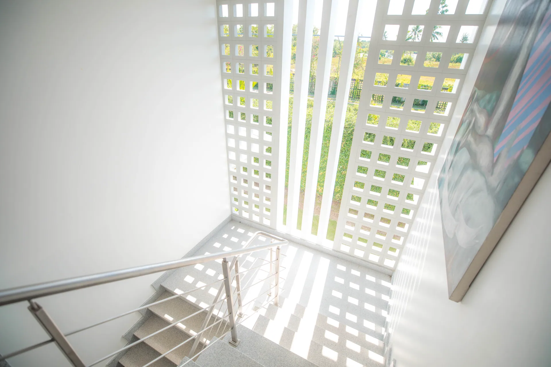 Staircase lit through a white breeze-block screen