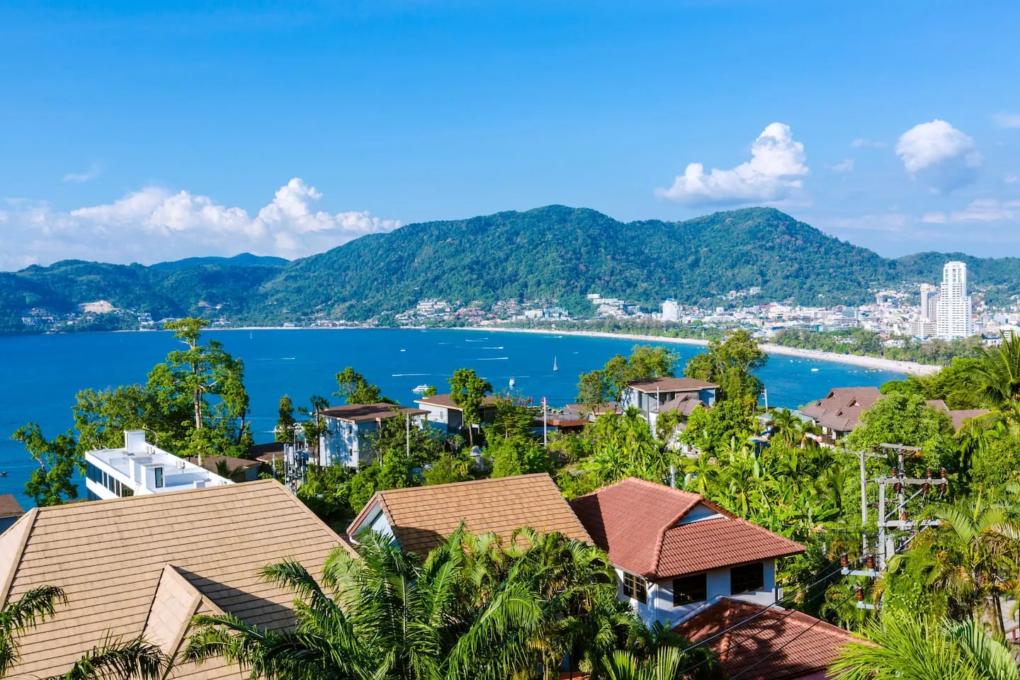 Patong Bay seen from the hillside, with the curve of the beach, the town and green hills beyond