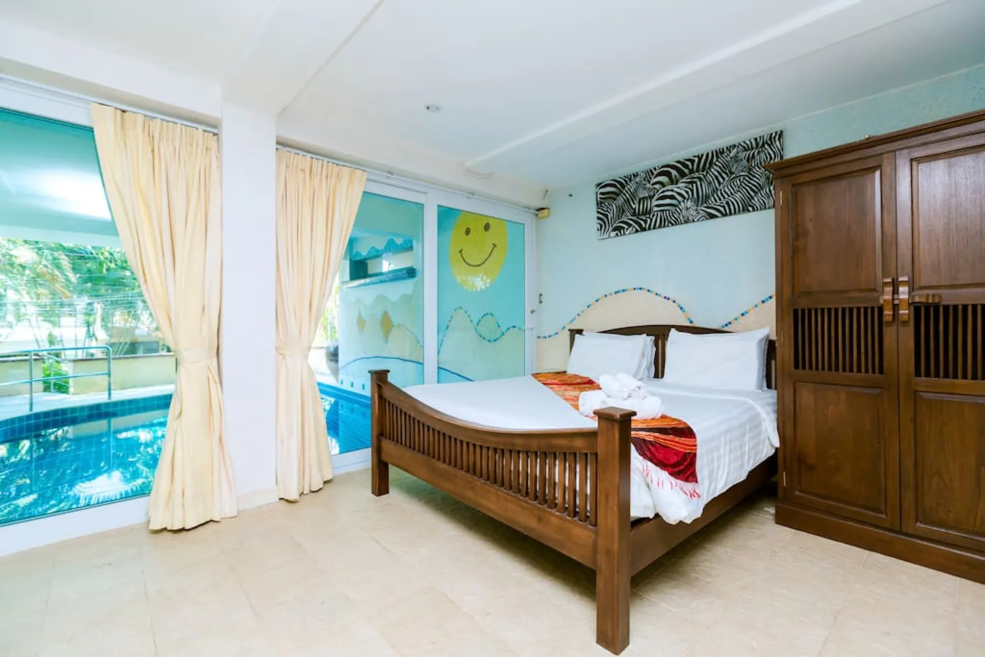 Ground-floor bedroom with a mosaic mural and glass doors opening onto the pool