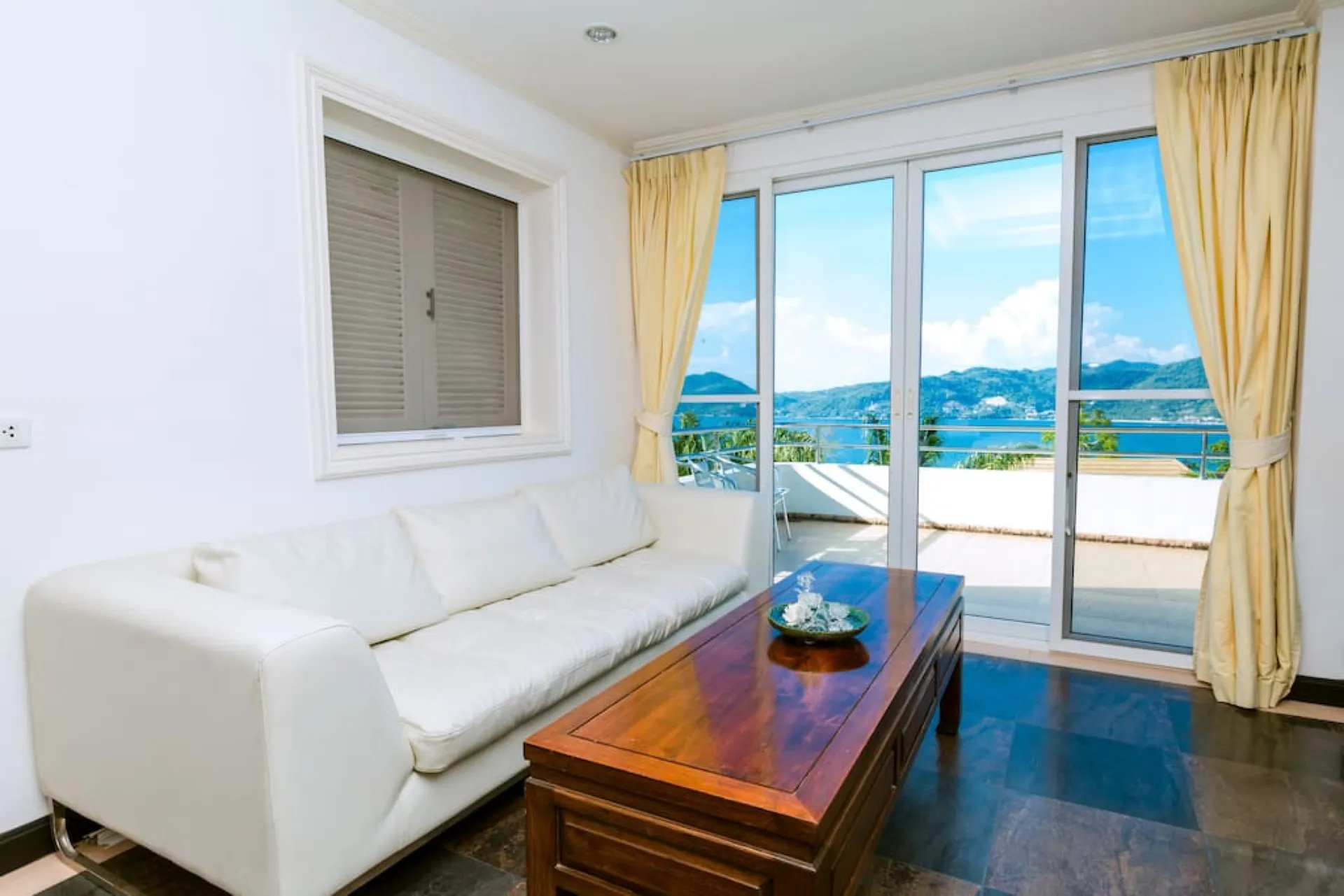 Upper lounge with a white leather sofa and glass doors to a terrace with a sea view