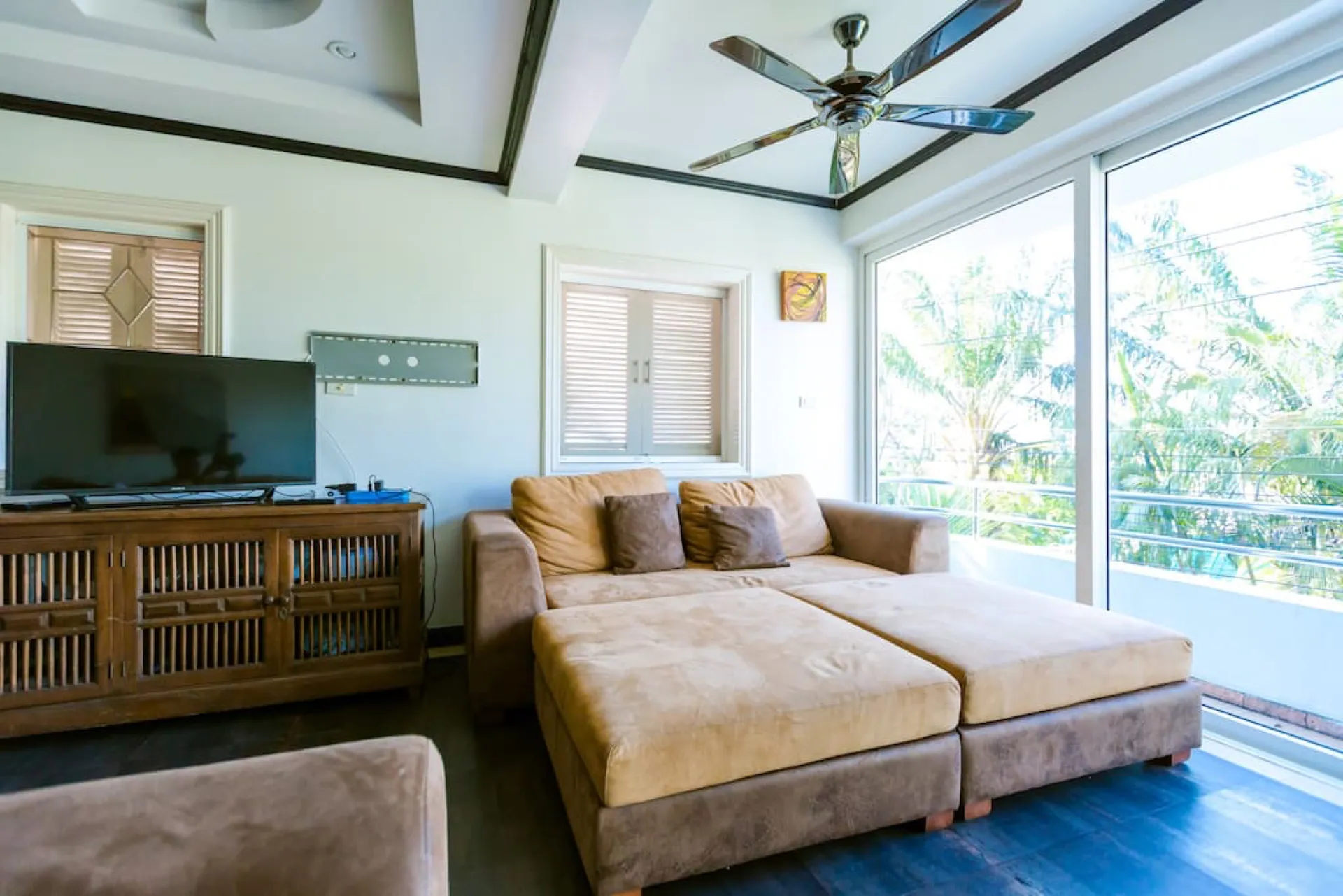 Family room with a TV, a wide suede chaise sofa and glass doors to a balcony