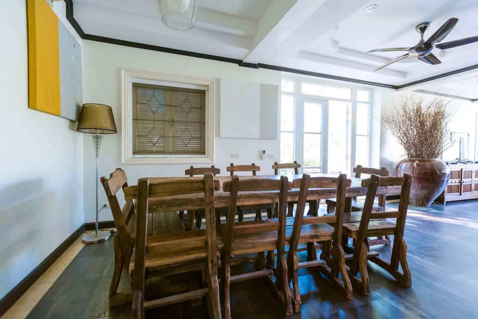 Long timber dining table with high-backed chairs beneath a ceiling fan