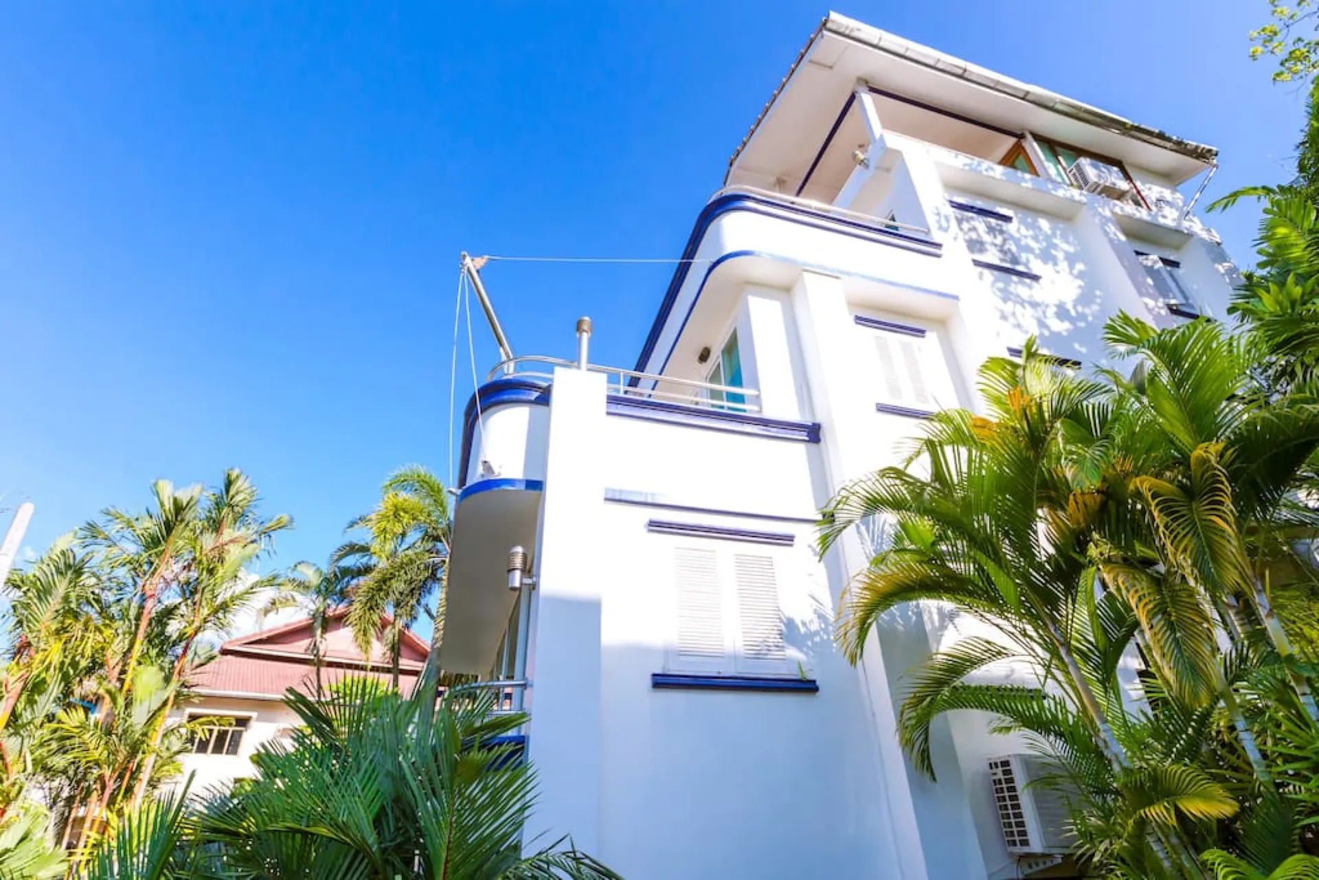 The white, multi-storey villa rising among palm trees under a blue sky