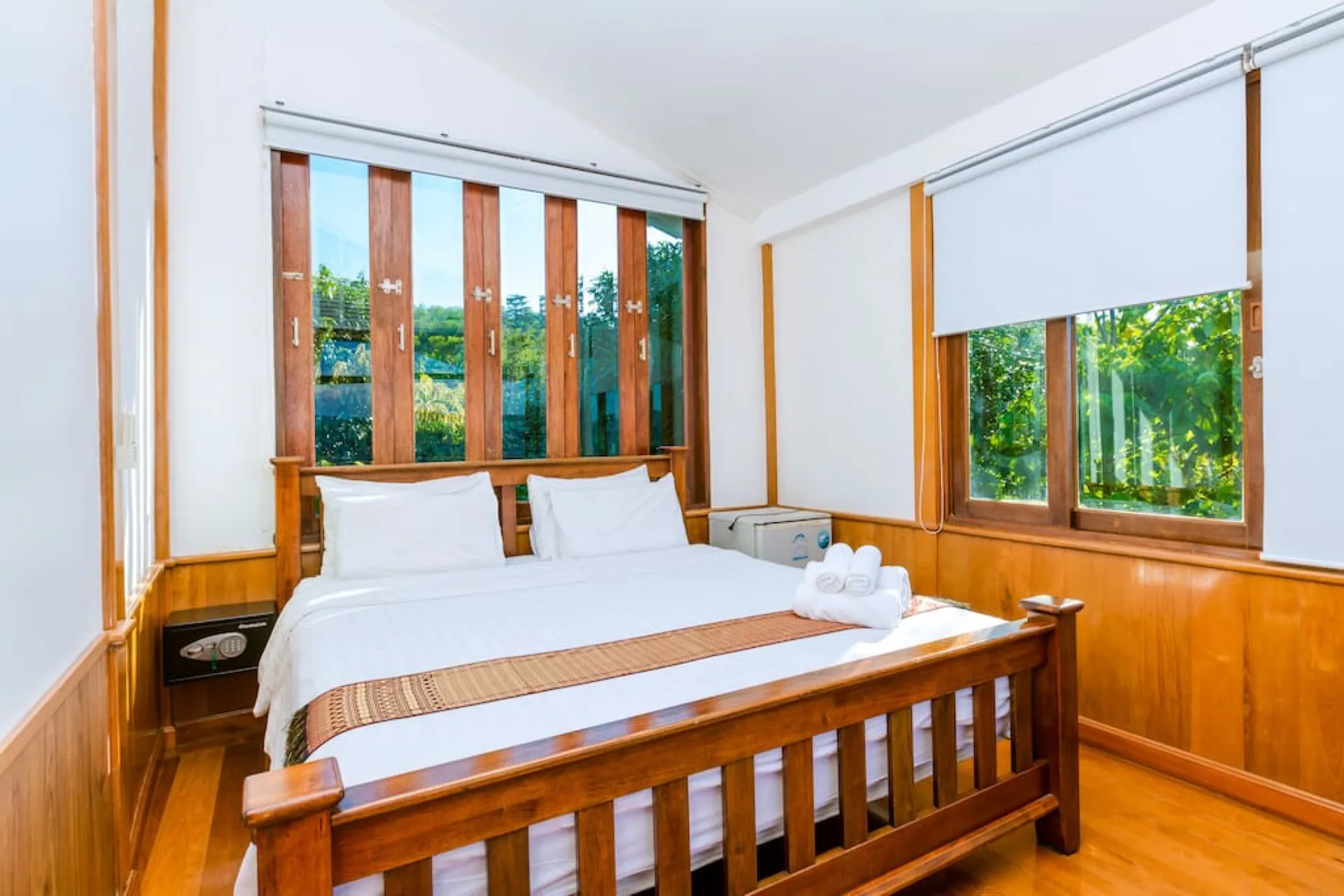 Timber-panelled bedroom with a slatted window screen and garden views