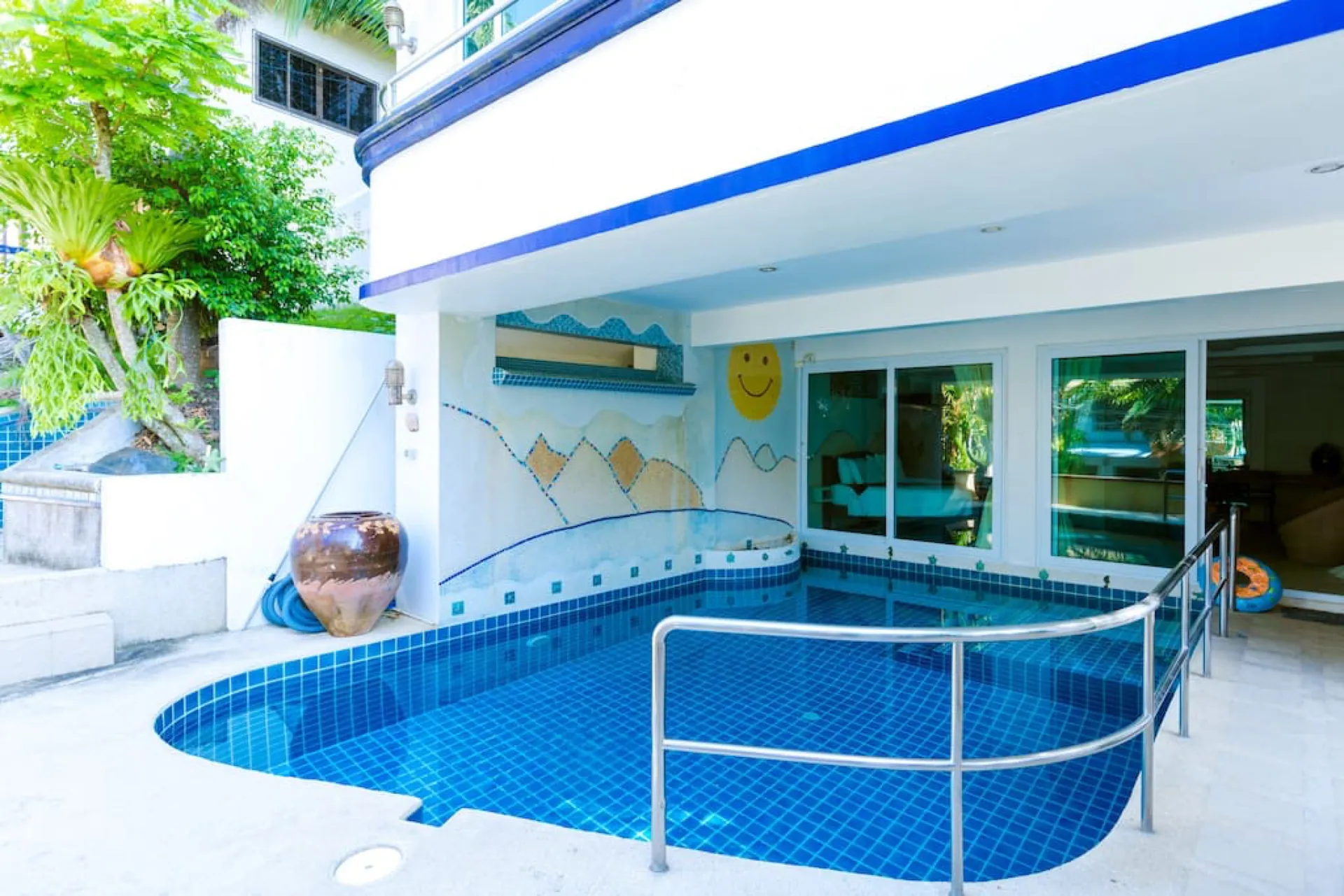 Private pool on the lower level, sheltered beneath the upper floors, with tropical plants alongside