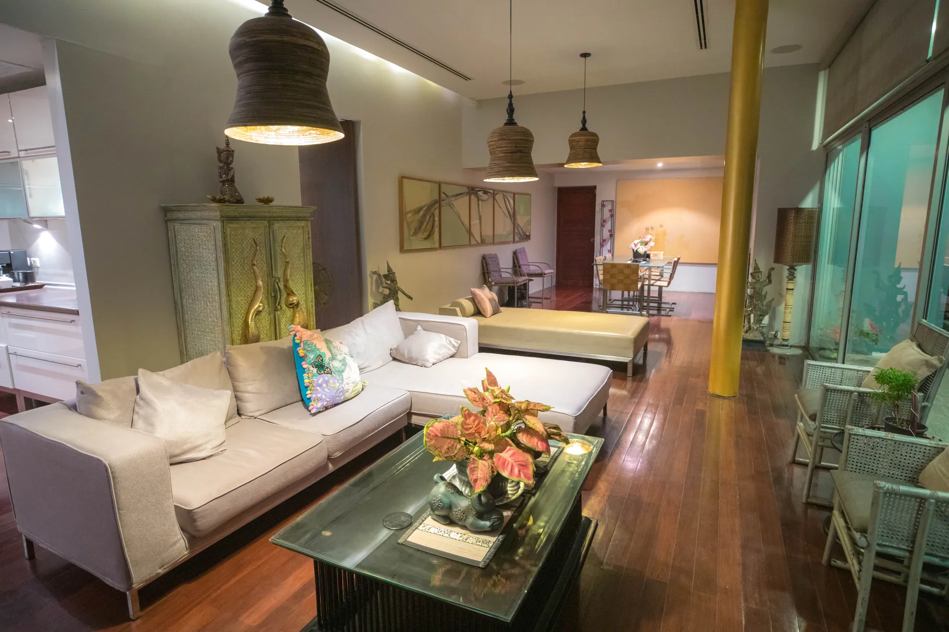 Living room with a white corner sofa, pendant lamps and glass walls to the terrace