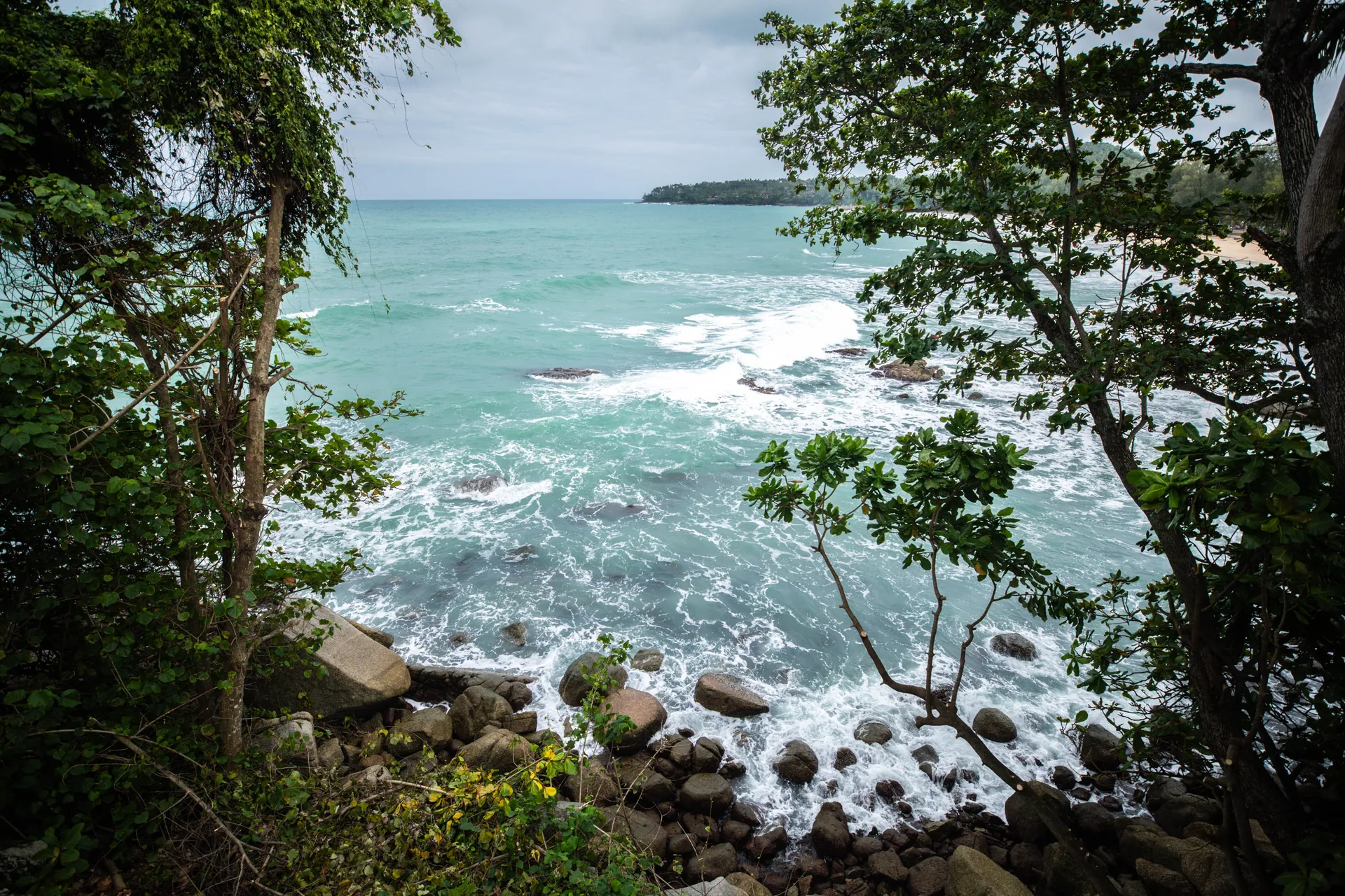 Waves breaking on the rocks below the villa, framed by trees