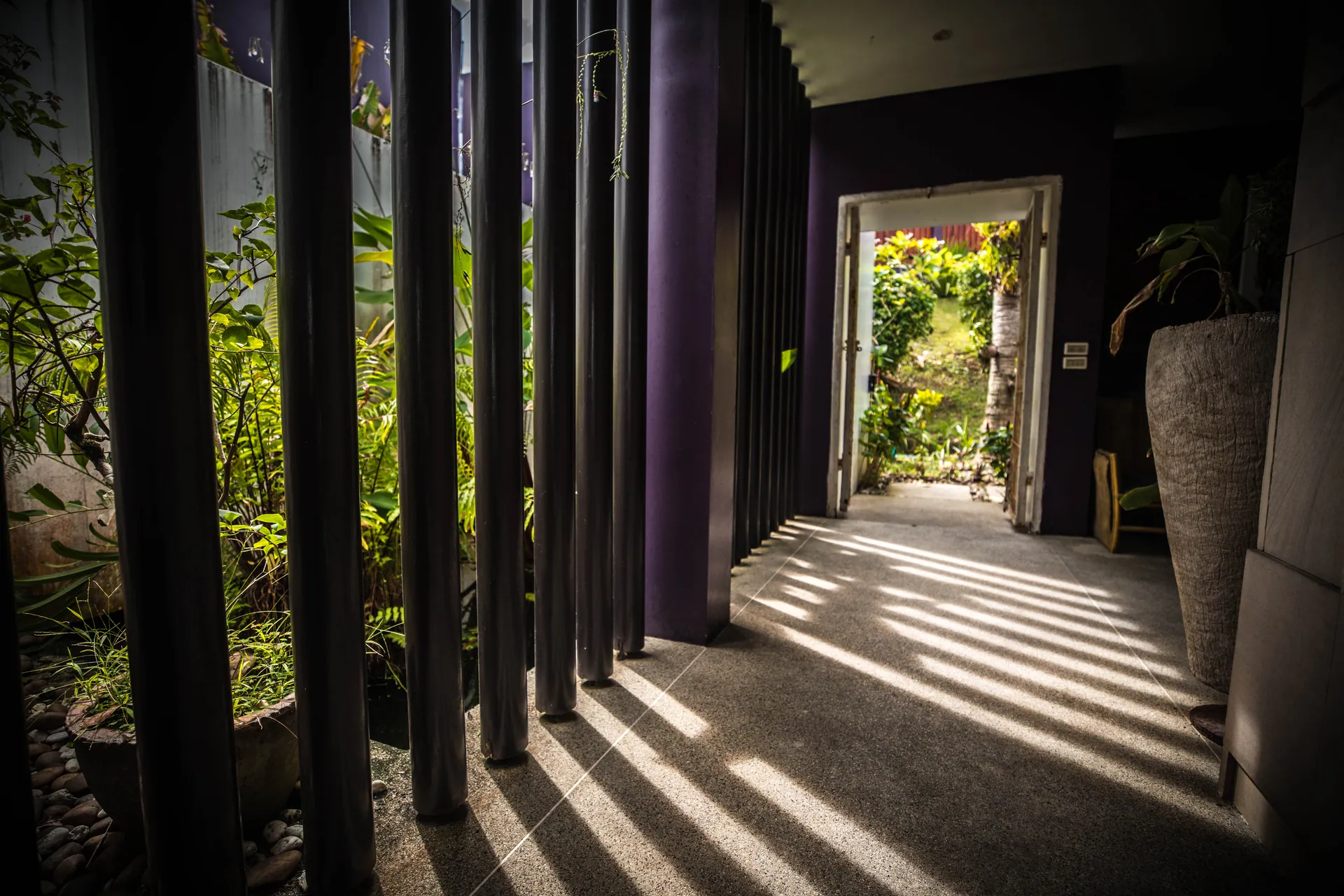 Entrance walkway with slatted screens casting stripes of light on the floor